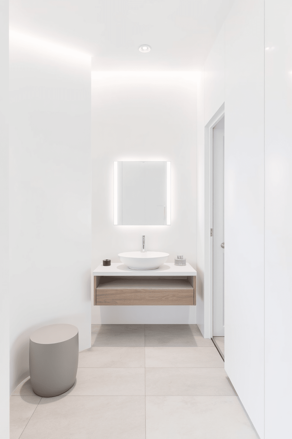 A minimalist bathroom design featuring clean lines and a serene ambiance. The space includes a floating vanity with a single basin and a sleek mirror above, complemented by soft lighting. The walls are painted in a crisp white, creating a bright and airy feel. The floor is adorned with large, light gray tiles, enhancing the minimalist aesthetic.