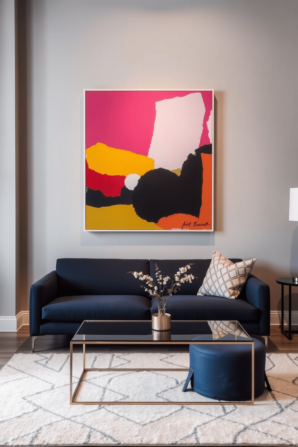 A modern apartment living room featuring bold artwork as the focal point. The walls are painted in a soft gray, allowing the vibrant colors of the artwork to pop. A sleek, low-profile sofa in a deep navy blue is positioned in front of the artwork. A minimalist coffee table made of glass and metal sits in the center, complemented by a plush area rug in neutral tones.