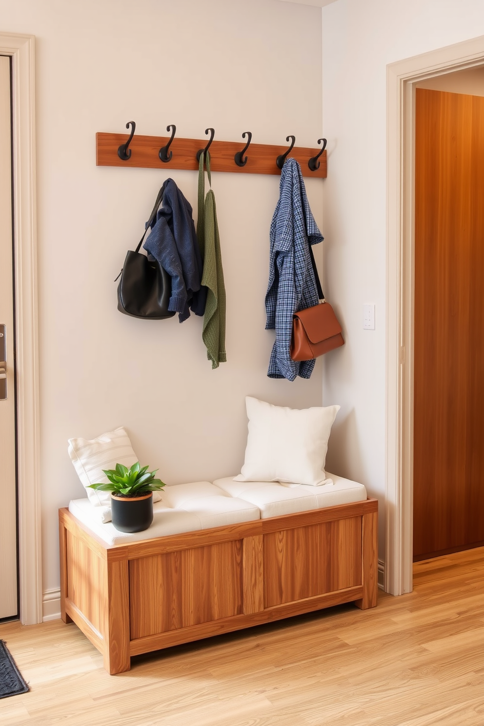 A cozy bench with storage is positioned against the wall in the apartment entryway. The bench features soft cushions and a warm wood finish, providing both comfort and functionality. Above the bench, a series of hooks are mounted for hanging coats and bags. A small potted plant sits next to the bench, adding a touch of greenery to the space.