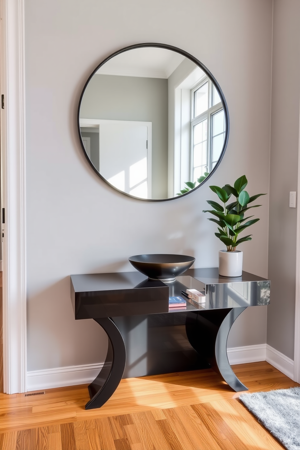 A stylish apartment entryway featuring a sleek console table with a glossy finish. Above the table, a large round mirror reflects natural light, creating an inviting atmosphere. The walls are adorned with a soft gray paint, complemented by a warm wooden floor. A decorative bowl sits on the console table, and a potted plant adds a touch of greenery to the space.