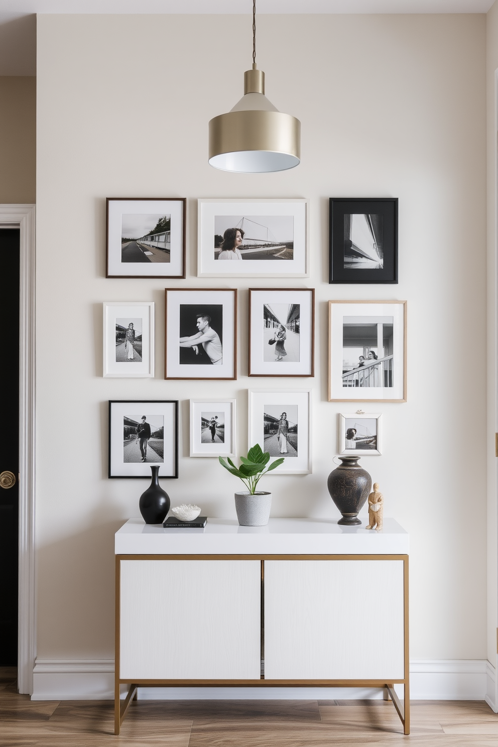 Create a gallery wall featuring a curated selection of framed photographs in various sizes. The wall is painted in a soft neutral color, providing a perfect backdrop for the art pieces. Incorporate a stylish console table beneath the gallery wall, adorned with decorative objects and a small potted plant. The entryway is illuminated by a modern pendant light, enhancing the welcoming atmosphere.