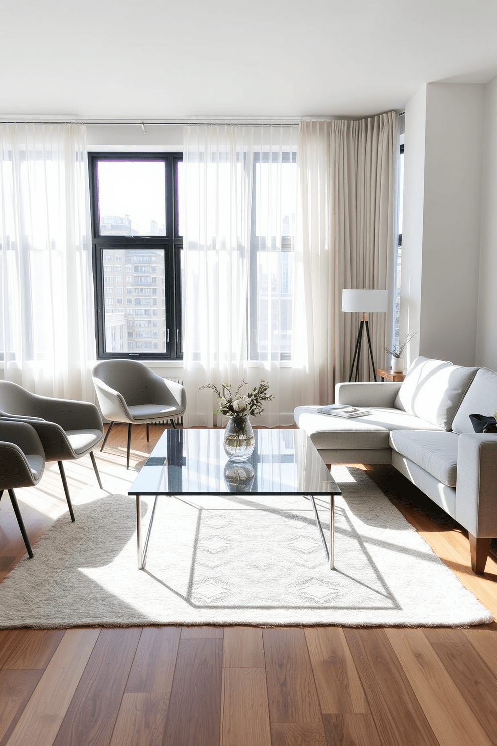 A bright and airy apartment living room features a light grey sofa with exposed wooden legs, creating an open and spacious feel. A glass coffee table sits in the center, reflecting light and enhancing the room's brightness. Accent chairs with slim profiles and metal legs are placed around the coffee table, adding a modern touch. Large windows dressed with sheer curtains allow natural light to flood the space, making it inviting and warm.