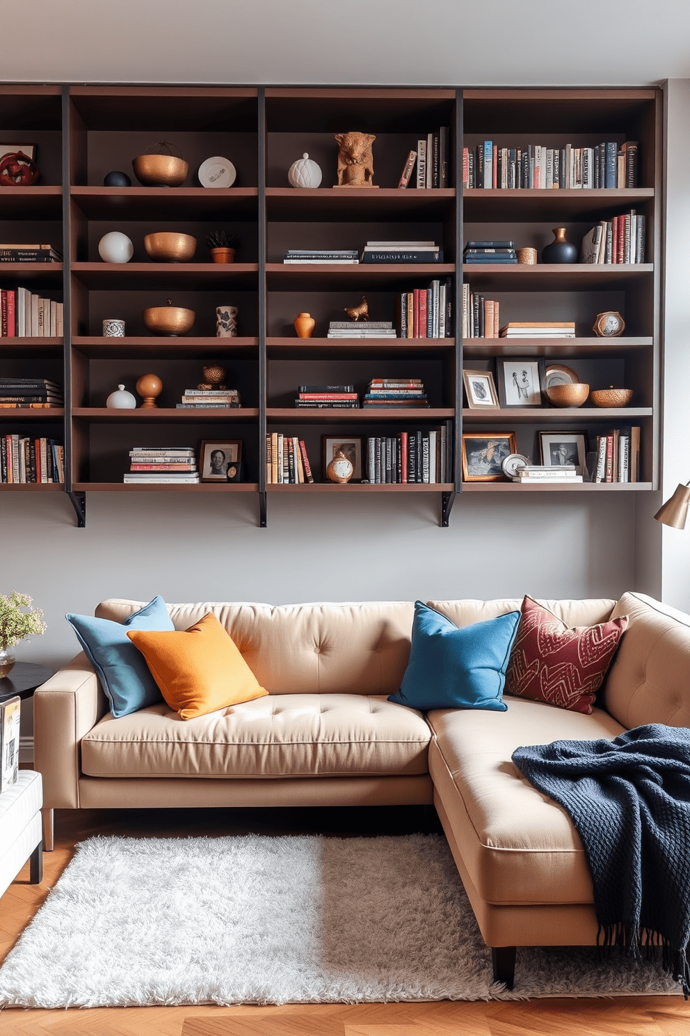 A stylish apartment living room featuring open shelving that showcases a curated collection of decorative items and books. The space is anchored by a plush sectional sofa in a neutral tone, complemented by vibrant throw pillows and a soft area rug.