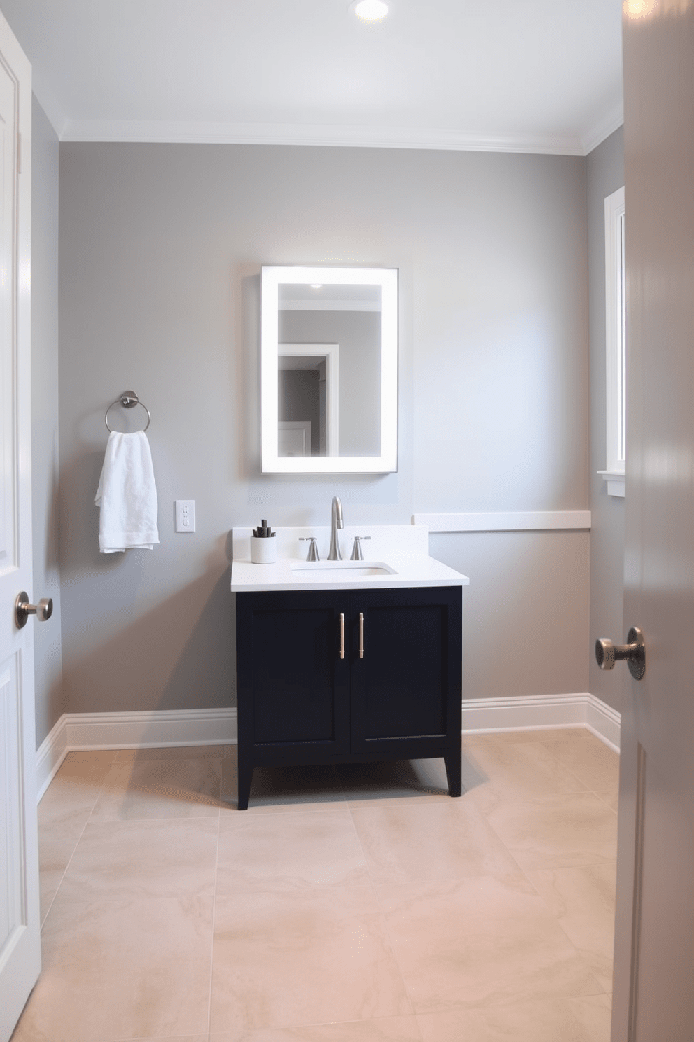 A cohesive color scheme unifies the basement bathroom, featuring soft gray walls and white trim that create a calming atmosphere. The flooring consists of large format tiles in a light beige, complementing the overall palette and enhancing the sense of space. The vanity is a sleek, modern design in a deep navy blue, topped with a crisp white quartz surface. Above the vanity, a stylish backlit mirror adds both functionality and a touch of elegance to the room.