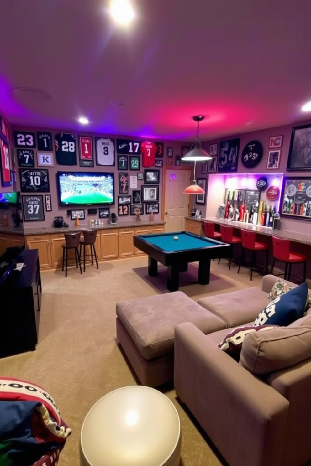 A vibrant basement game room filled with sports memorabilia adorning the walls. Framed jerseys and signed photographs create a personalized atmosphere, while a large sectional sofa invites relaxation in front of a big-screen TV. The room features a custom-built bar with high stools, showcasing various sports-themed decorations. A pool table sits in the center, surrounded by colorful accent lighting that enhances the energetic vibe of the space.