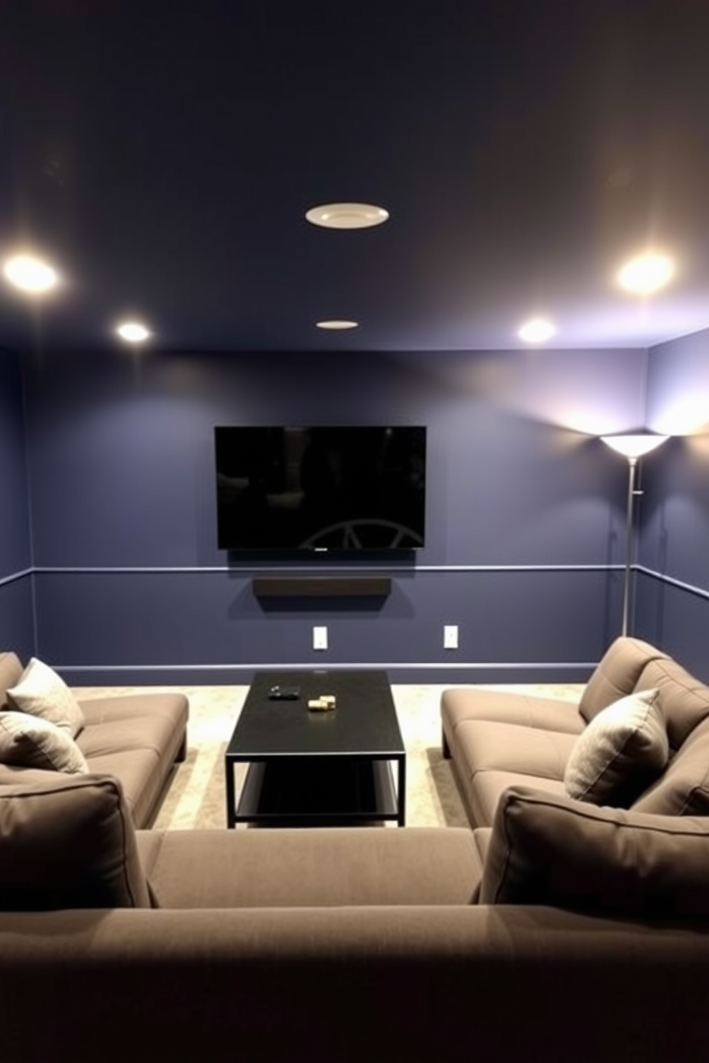 A contemporary basement game room featuring a wall-mounted TV as the focal point. The room is designed with a comfortable sectional sofa in dark gray, positioned for optimal viewing, and a sleek coffee table in the center. The walls are painted in a deep navy blue, creating a cozy atmosphere. Ambient lighting is provided by recessed lights and stylish floor lamps, enhancing the inviting feel of the space.