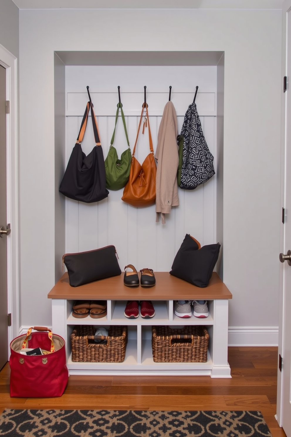 A functional drop zone for bags and shoes features a built-in bench with storage underneath for shoes and baskets for smaller items. The walls are painted in a light gray color, and hooks are installed above the bench for hanging bags and jackets.