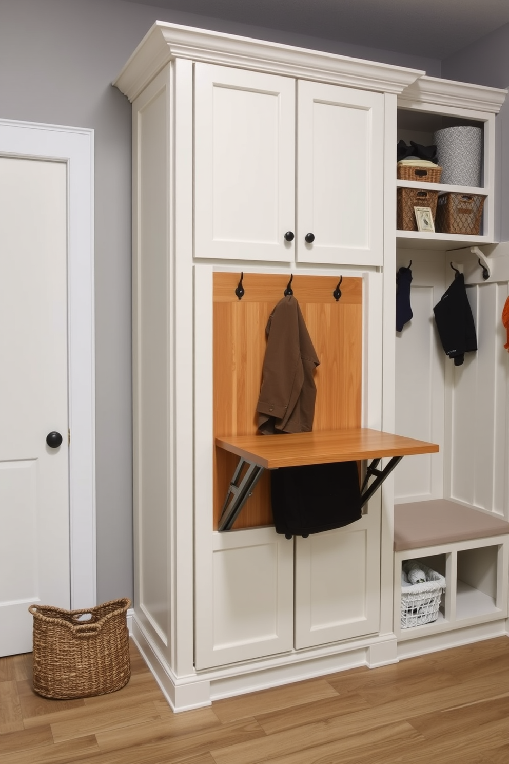 A wall-mounted folding table is installed in the mudroom, providing a practical space for quick tasks and organization. The table is finished in a warm wood tone that complements the surrounding cabinetry and adds a touch of elegance. The mudroom features ample storage solutions, including built-in cubbies and hooks for easy access to coats and bags. The walls are painted in a soft gray shade, creating a welcoming atmosphere that enhances the functionality of the space.