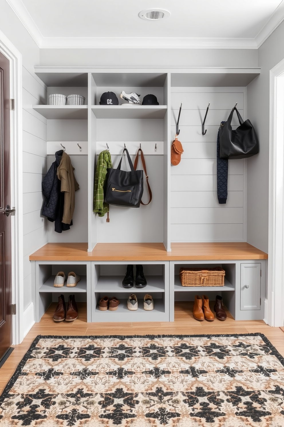 A modern mudroom featuring hidden compartments for discreet storage. The design includes built-in benches with lift-top seats that reveal storage space underneath, perfect for shoes and bags. The walls are adorned with shiplap in a soft gray tone, complemented by hooks for coats and bags. A durable, patterned rug lies on the floor, adding warmth and character to the space while providing a practical solution for muddy shoes.