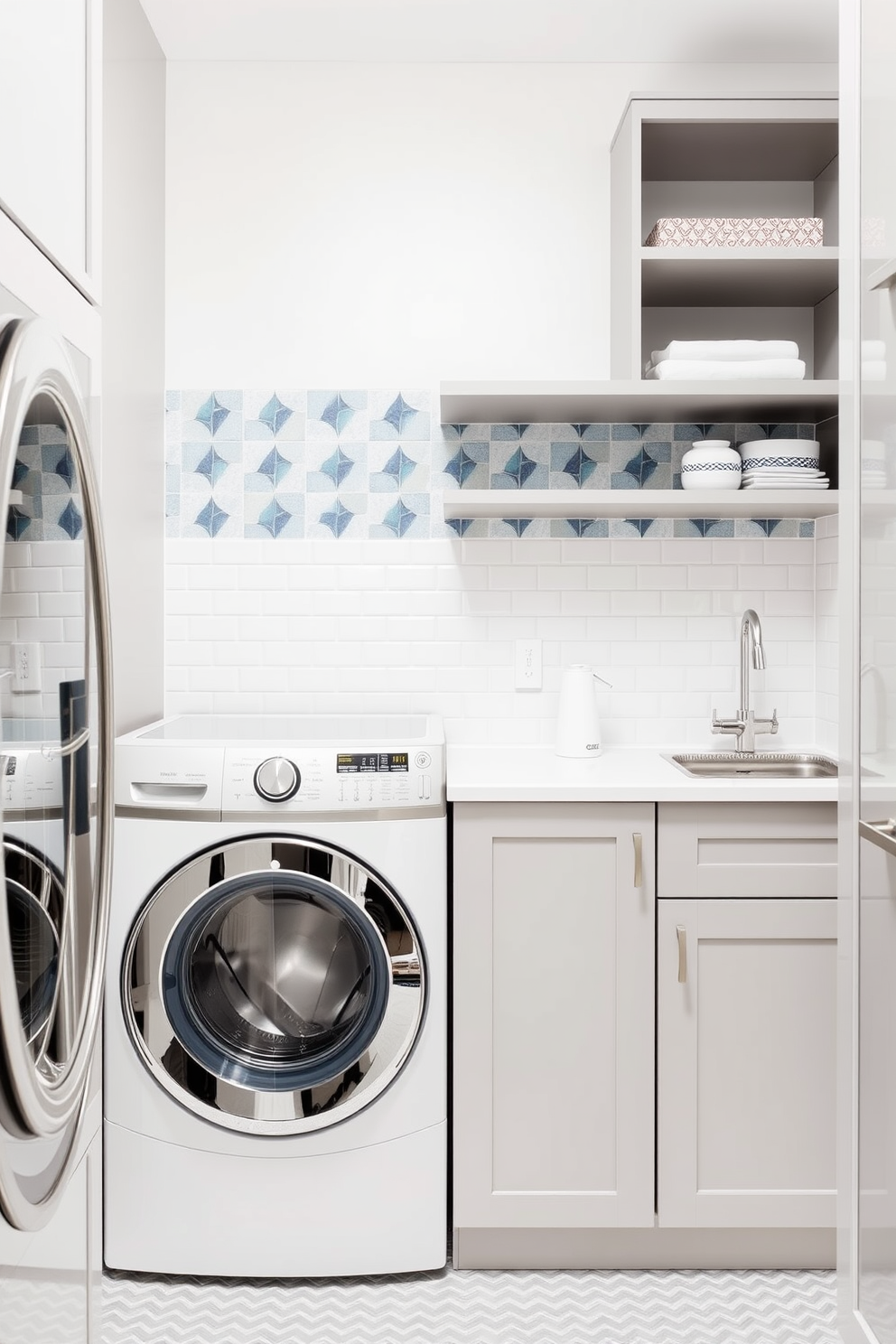 A stylish backsplash adorns the wall behind the laundry area, featuring geometric tiles in shades of blue and white. The laundry room combines functionality with elegance, showcasing a sleek washer and dryer set beneath a countertop for folding clothes. A modern utility sink is positioned next to the appliances, complemented by open shelving above for easy access to detergents and supplies. The overall color scheme is light and airy, with soft gray cabinetry that enhances the space's contemporary feel.