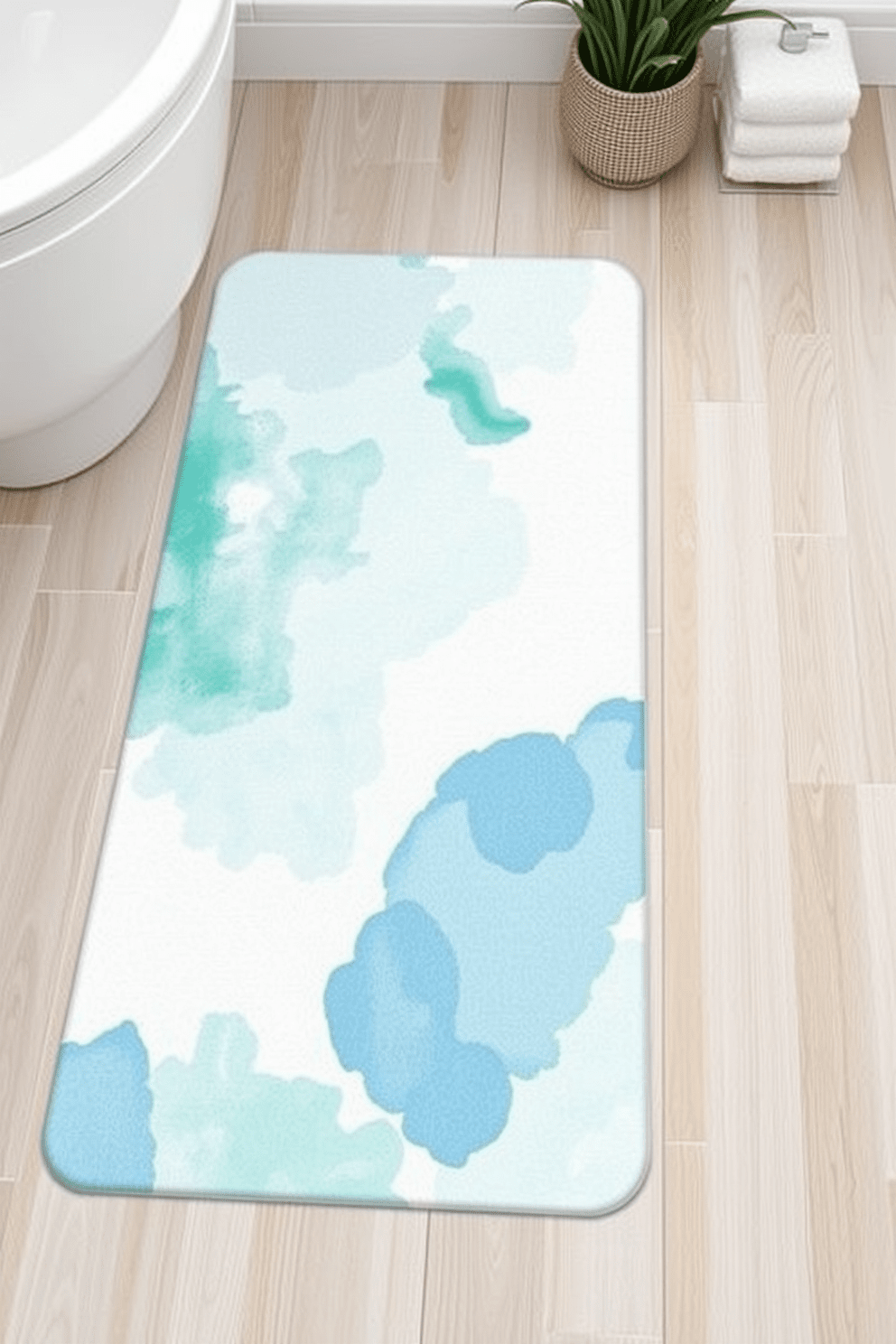 A serene bathroom rug design featuring soft watercolor patterns in shades of blue and green. The rug complements a light-colored wooden floor and adds a calming touch to the overall space. Delicate swirls and abstract shapes create a soothing visual effect that enhances the tranquility of the bathroom. This design invites relaxation and pairs beautifully with neutral bathroom decor.