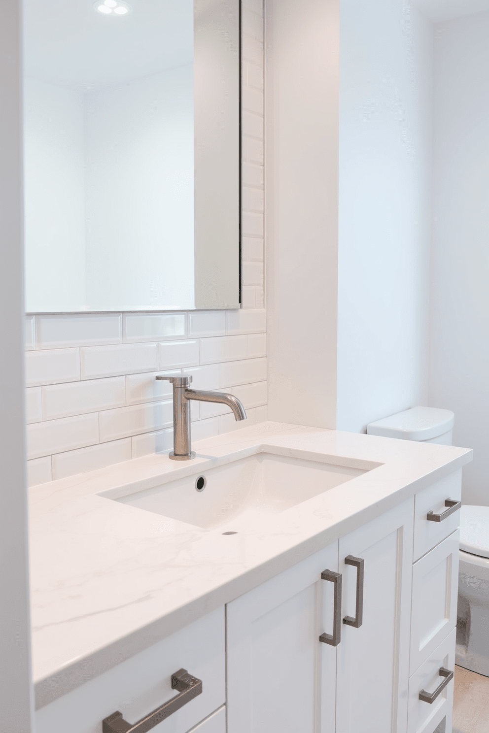 A sleek bathroom featuring an under-mount sink seamlessly integrated into a beautiful quartz countertop. The cabinetry is finished in a soft white, providing a clean and modern aesthetic. The wall behind the sink is adorned with elegant subway tiles in a glossy finish, creating a timeless backdrop. A stylish faucet in brushed nickel complements the overall design, adding a touch of sophistication.