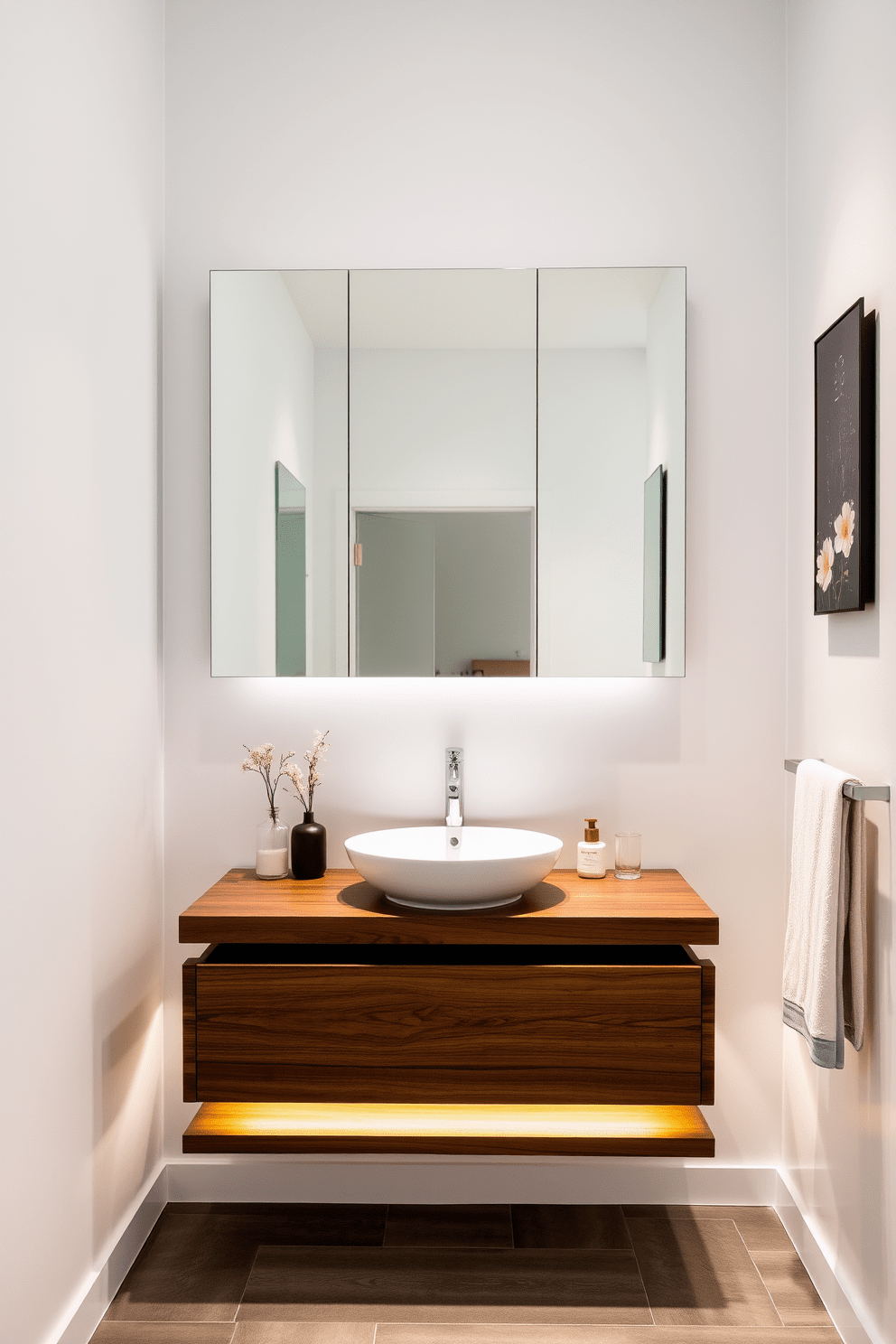 A modern floating vanity with sleek lines and under-sink lighting creates a stunning focal point in the bathroom. The vanity is crafted from rich walnut wood, complementing the soft white walls and providing a warm contrast. The sink is a minimalist vessel style, elegantly positioned on the countertop. Surrounding the sink, a series of decorative items add a touch of personality, while the under-sink lighting casts a soft glow, enhancing the overall ambiance.