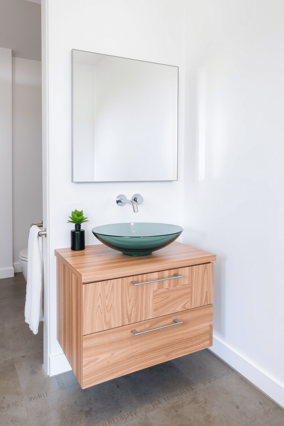 A sleek glass vessel sink sits atop a minimalist wooden vanity, showcasing contemporary elegance. The surrounding countertop is adorned with stylish accessories, including a small potted plant and a decorative soap dispenser. The walls are painted in a crisp white, enhancing the modern aesthetic of the space. Underfoot, polished concrete flooring provides a chic contrast, completing the sophisticated bathroom design.