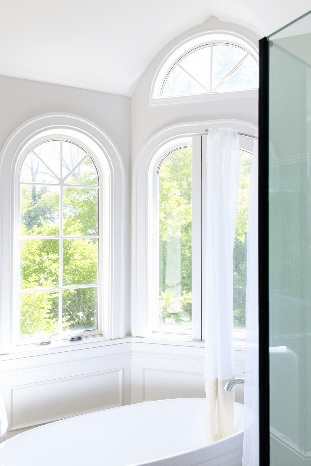 A bathroom featuring arched windows that allow natural light to flood the space. The windows are framed in sleek white wood, creating a bright and airy atmosphere. The arched design adds a touch of elegance, complementing the modern fixtures in the room. Soft sheer curtains drape elegantly to enhance privacy while maintaining the lightness of the space.