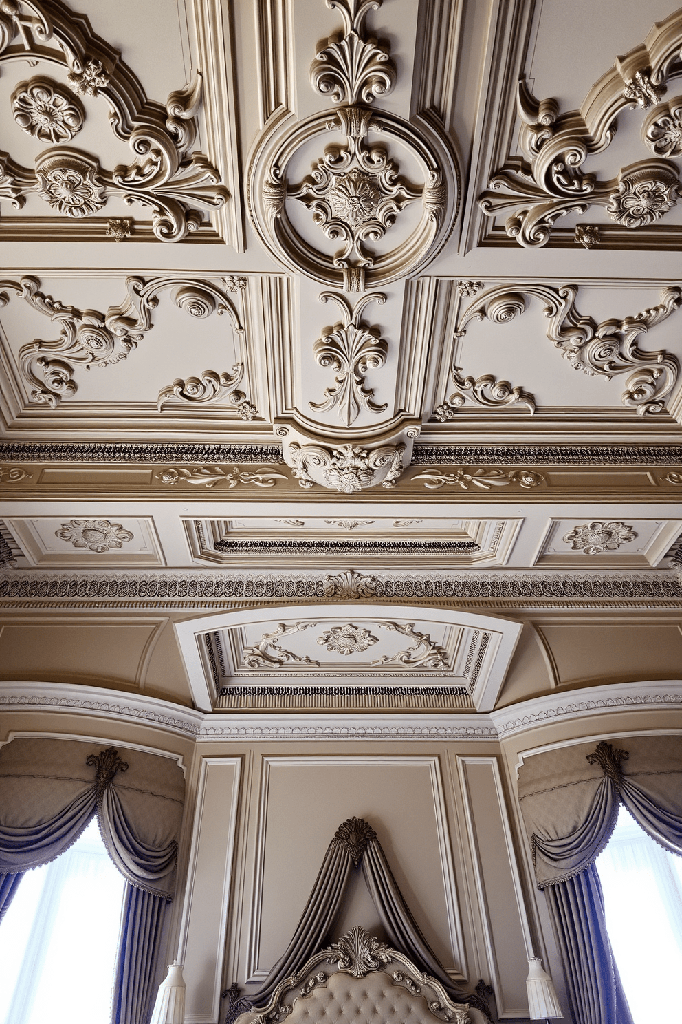 A luxurious bedroom featuring elegant crown molding that adds a sophisticated finish to the space. The ceiling is adorned with intricate designs, creating a sense of grandeur and depth in the room.