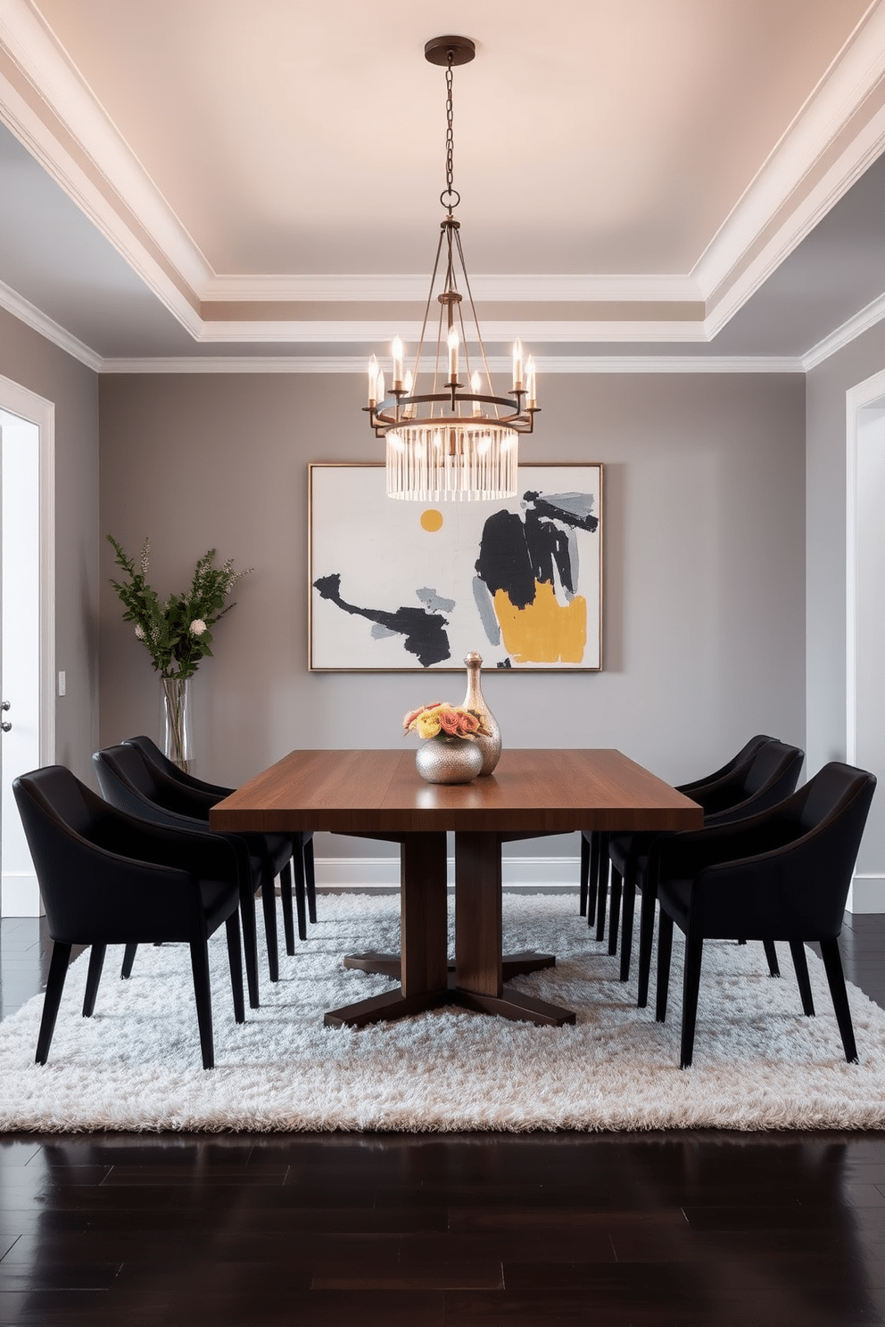 A stylish dining area features elegant black dining chairs arranged around a sleek wooden table. The walls are painted in a soft gray tone, and a statement chandelier hangs above, illuminating the space with a warm glow. The room is accented with a large abstract painting that adds a pop of color. A plush area rug beneath the table ties the design together, creating a cozy atmosphere that invites gatherings.