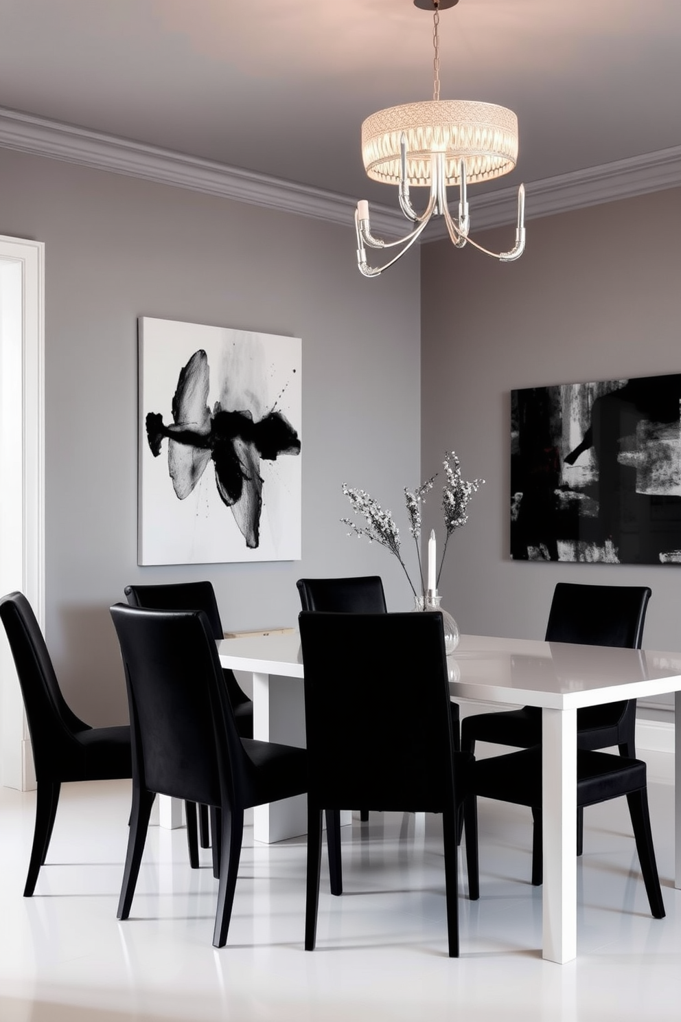 Chic black chairs are elegantly arranged around a sleek white dining table. The room features a modern chandelier overhead, casting a warm glow that enhances the sophisticated ambiance. The walls are painted in a soft gray tone to create a striking contrast with the black furniture. A large piece of abstract art adorns one wall, adding a touch of color and personality to the space.