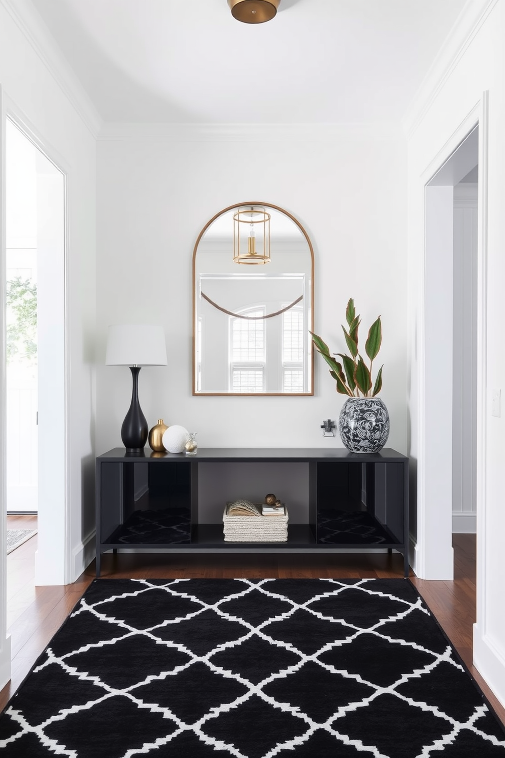 A stunning foyer features a layered black and white patterned rug that adds depth and texture to the space. The walls are painted in a crisp white, complemented by a sleek black console table adorned with decorative accents and a stylish mirror above it.