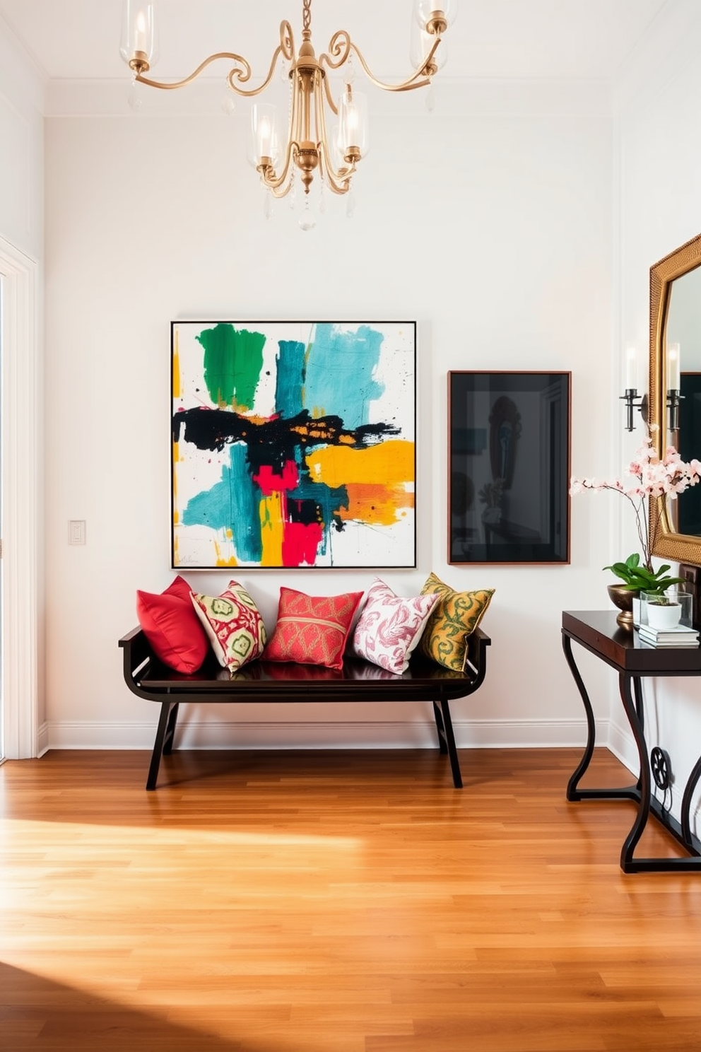 A sleek black bench is positioned against a bright white wall, adorned with an array of colorful pillows in various patterns and textures. The floor is polished hardwood, and a large abstract painting hangs above the bench, adding a vibrant focal point to the space. The foyer features elegant lighting fixtures that cast a warm glow, creating an inviting atmosphere. A stylish console table sits nearby, decorated with decorative items and a small potted plant for a touch of greenery.