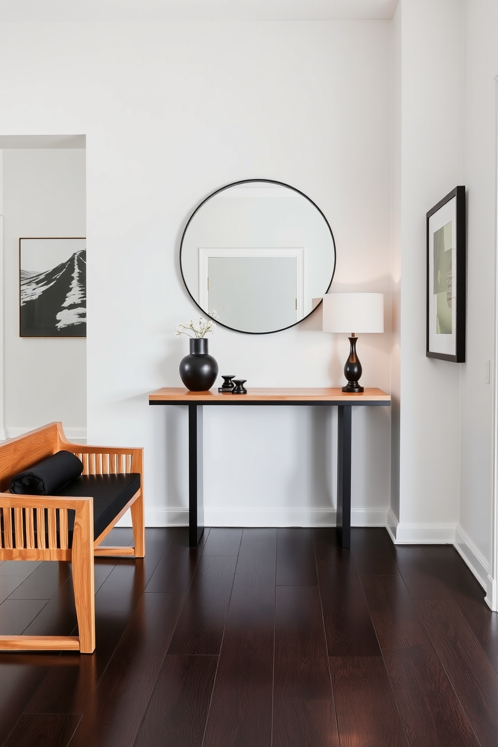 A modern foyer featuring a striking combination of black and wood furniture. The centerpiece is a sleek black console table with a natural wood top, elegantly paired with a large round mirror above it. To the side, a stylish wooden bench with black cushions offers a comfortable seating area. The walls are adorned with minimalist artwork, and the flooring is a rich dark hardwood that enhances the overall aesthetic.