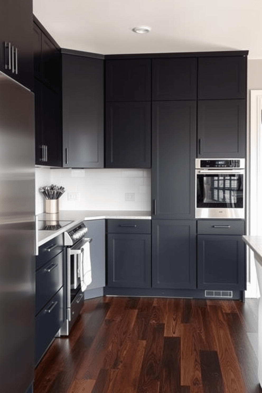 A sleek black kitchen featuring dark wood floors that add warmth and depth to the space. The cabinetry is designed in a modern style with a matte black finish, complemented by stainless steel appliances.