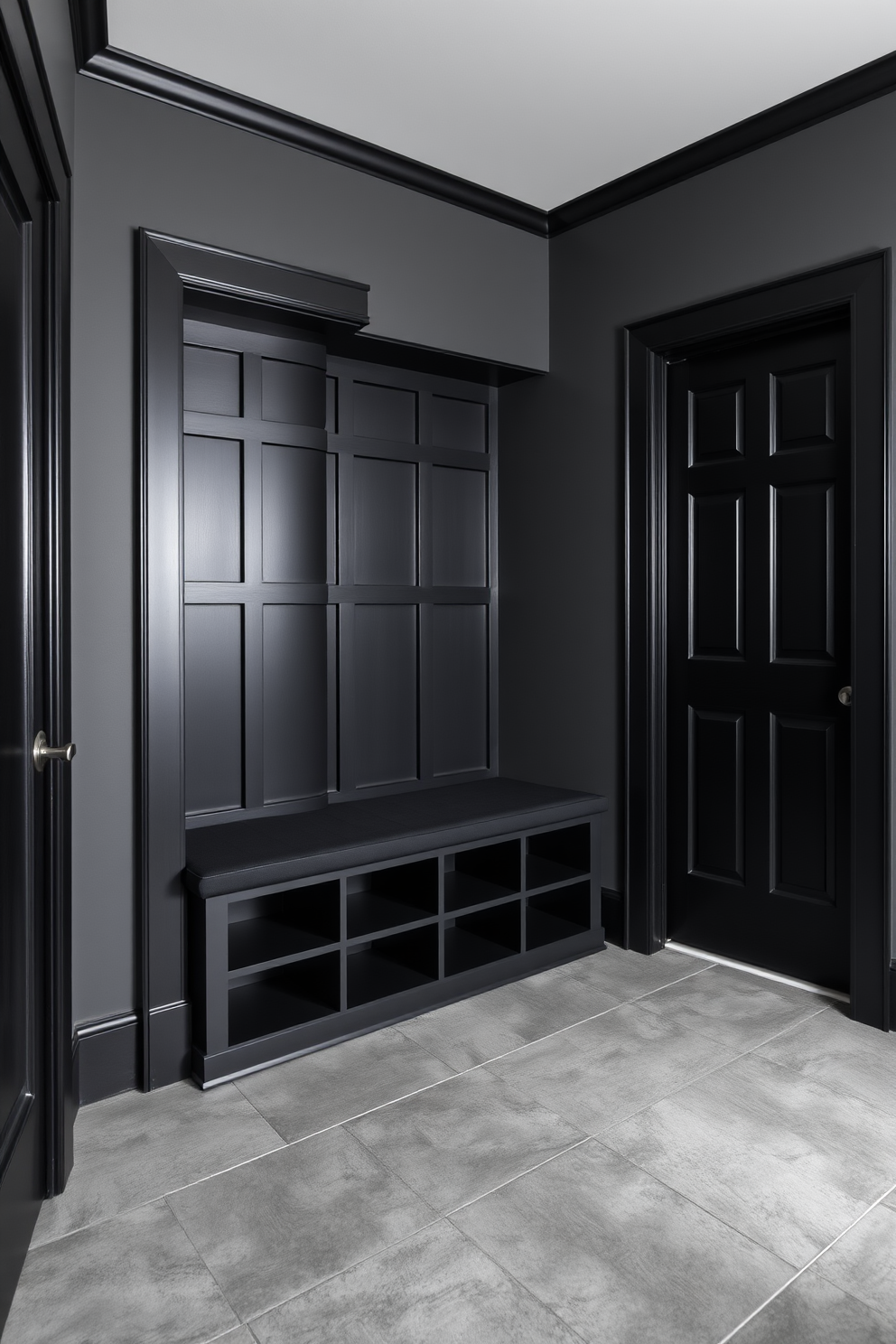 A stylish mudroom featuring a cohesive black and gray color scheme. The walls are painted in a deep charcoal gray, while the trim and doors are a sleek matte black. A built-in bench with storage cubbies sits against one wall, upholstered in a soft black fabric. The flooring consists of large gray tiles with a subtle texture, enhancing the modern aesthetic.