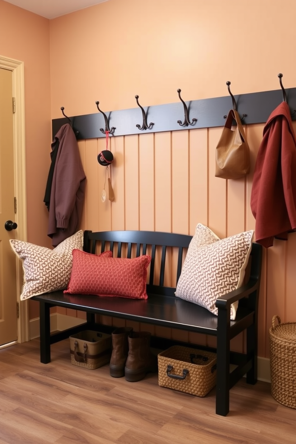 A cozy mudroom featuring a cottage-style black bench adorned with soft, colorful cushions. The walls are painted in a warm, inviting hue, and rustic hooks are mounted for hanging jackets and bags.