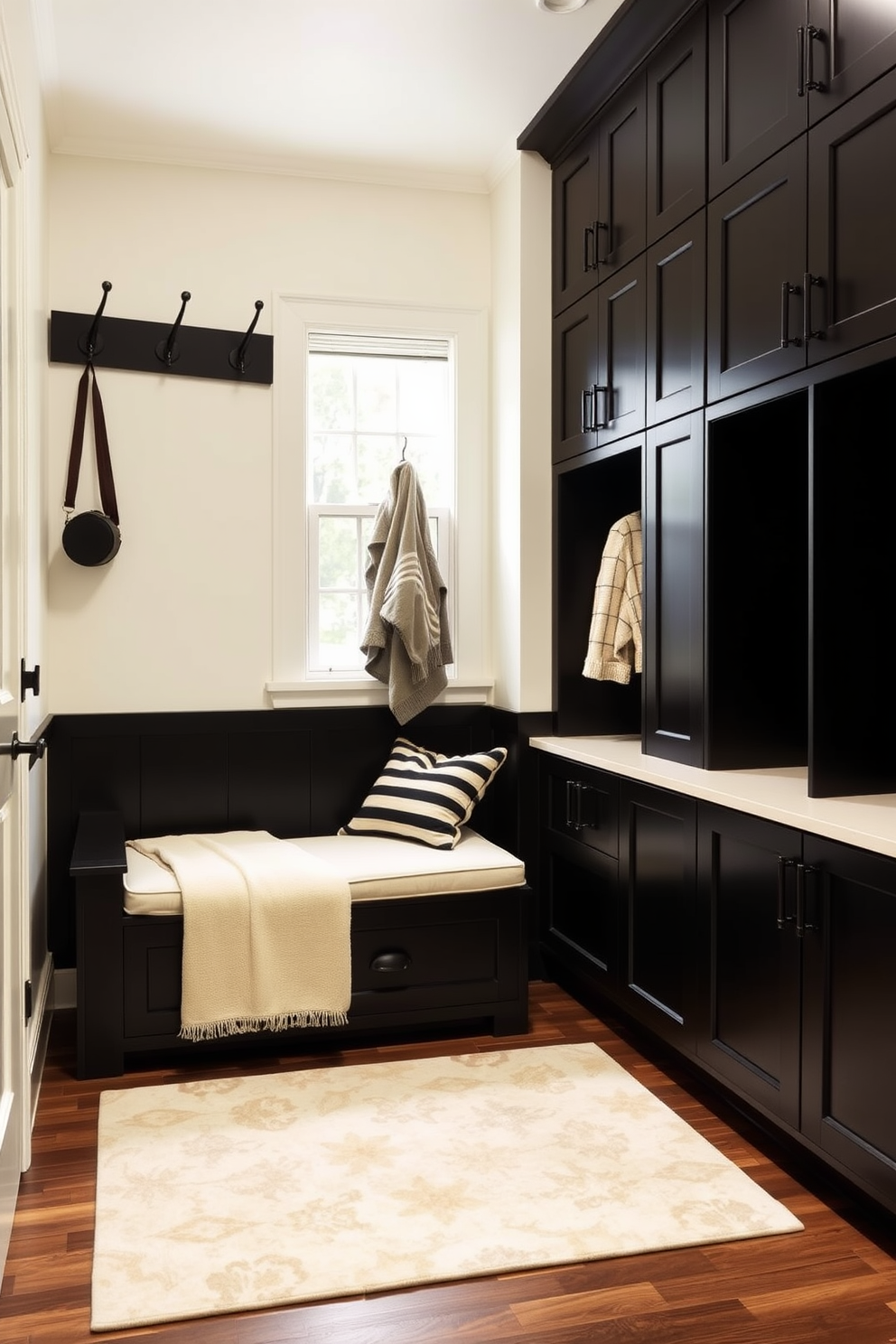 A stylish mudroom featuring a striking black and cream color contrast. The walls are painted in a soft cream shade, while the cabinetry and built-in benches are finished in a deep matte black. Sleek black hooks line the wall for hanging coats, and a large cream area rug adds warmth to the space. A stylish storage bench with cream cushions sits beneath a window, providing both comfort and functionality.