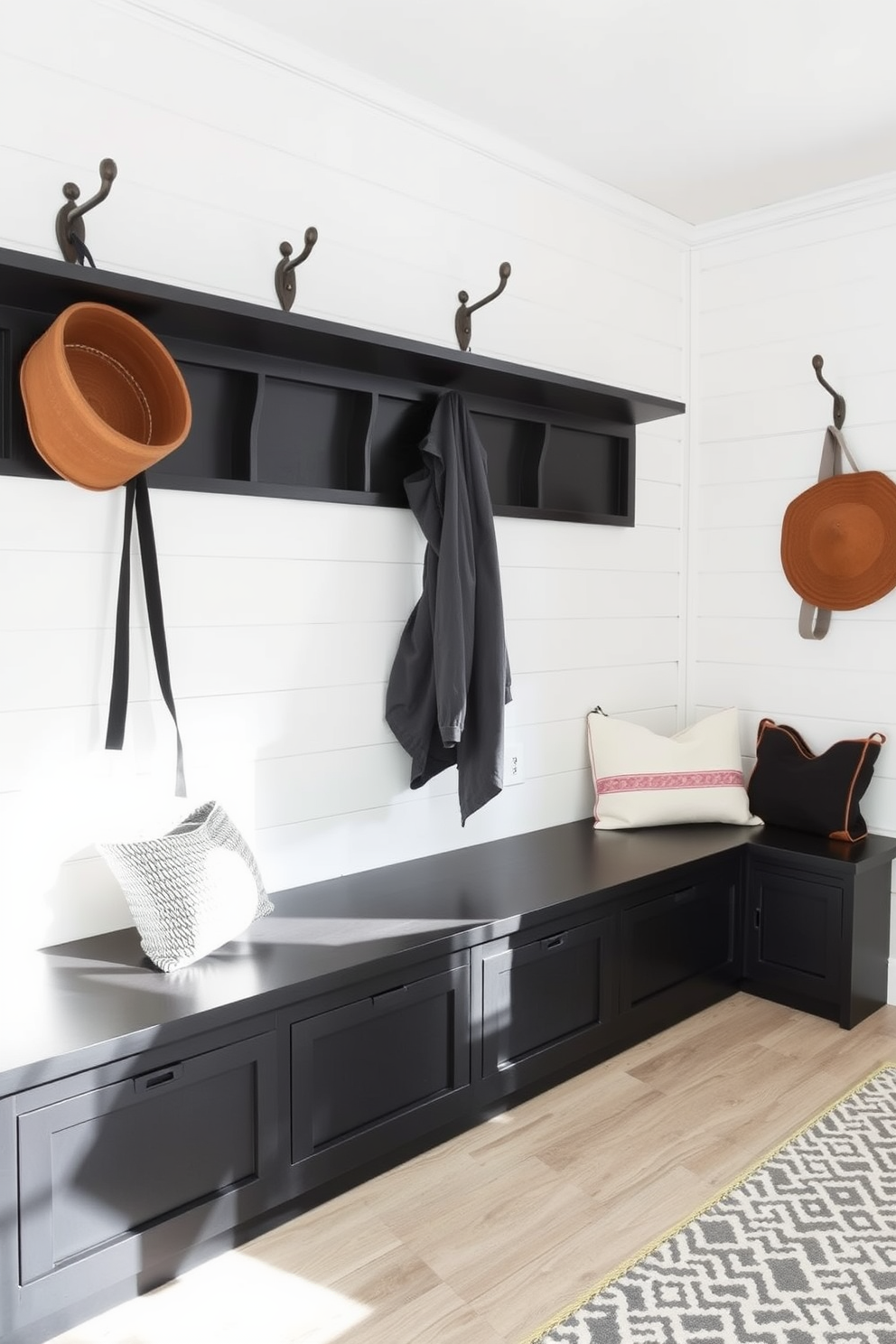 A modern farmhouse mudroom features black bench seating with ample storage underneath. The walls are adorned with shiplap in a soft white hue, and rustic hooks are mounted for hanging coats and bags.