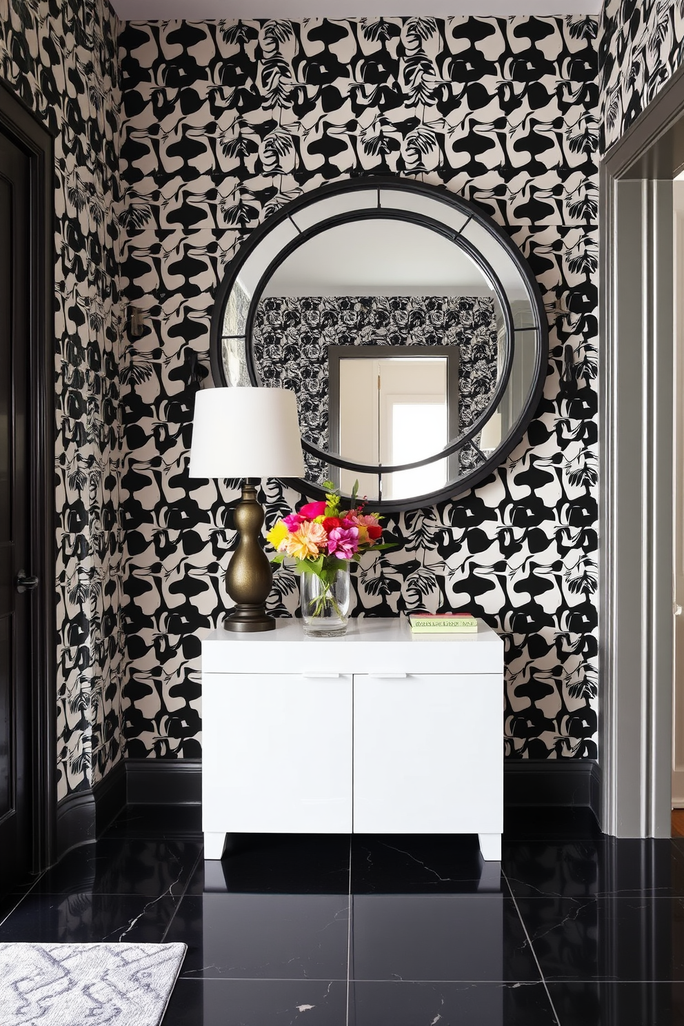 A whimsical foyer adorned with black and white patterned wallpaper that creates a striking visual impact. The floor features a sleek black tile that contrasts beautifully with the playful patterns on the walls. A stylish console table in a glossy white finish sits against the wallpaper, topped with a decorative lamp and a vibrant floral arrangement. An oversized round mirror with a black frame hangs above the console, reflecting the unique design elements of the space.