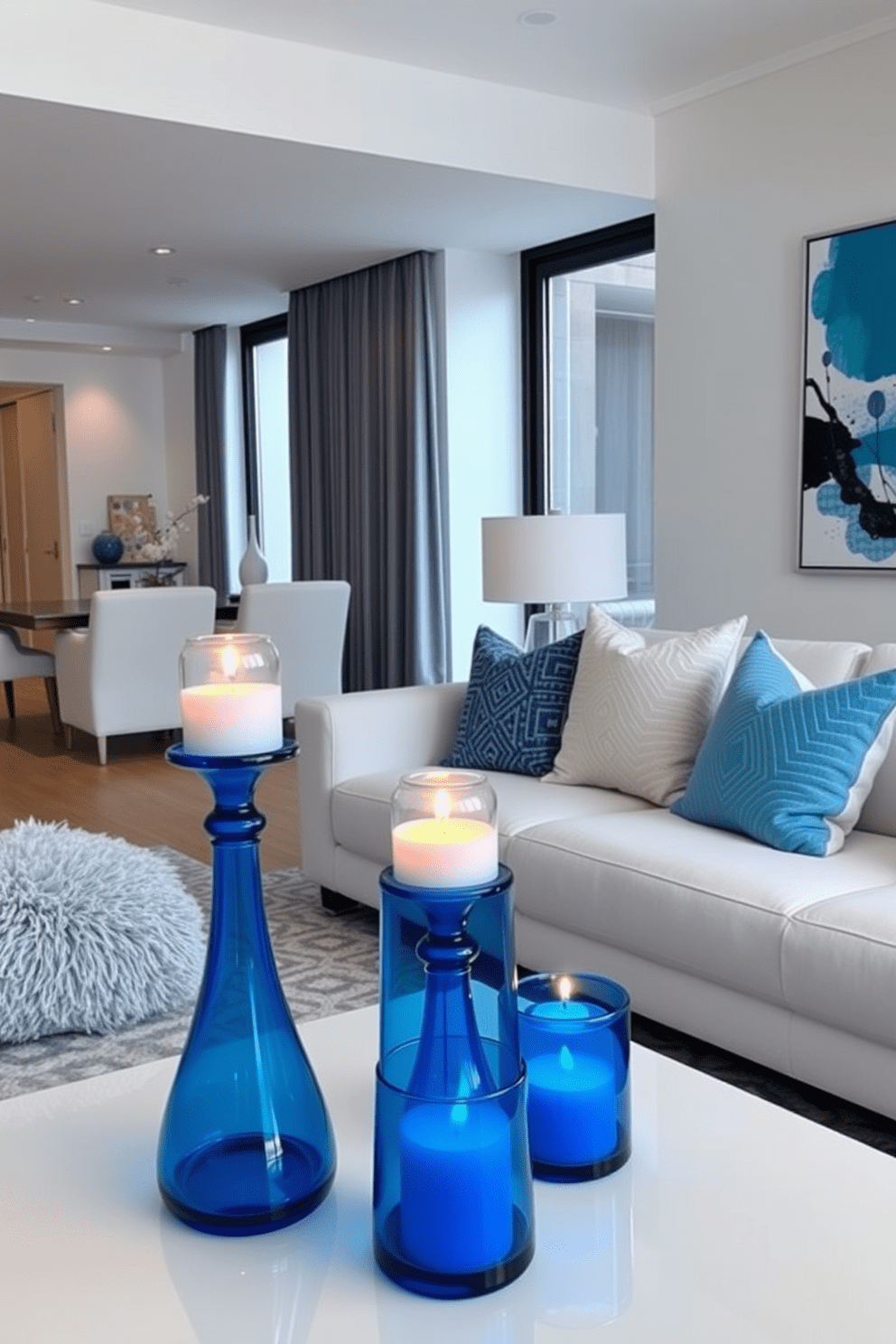 A serene living room setting featuring blue glass candle holders that cast a soft glow throughout the space. The overall design incorporates modern furniture with clean lines and a cohesive color palette centered around shades of blue and white. The apartment layout is open and airy, maximizing natural light with large windows. Accent pieces, such as plush cushions and abstract artwork, complement the blue theme while adding warmth and texture to the environment.