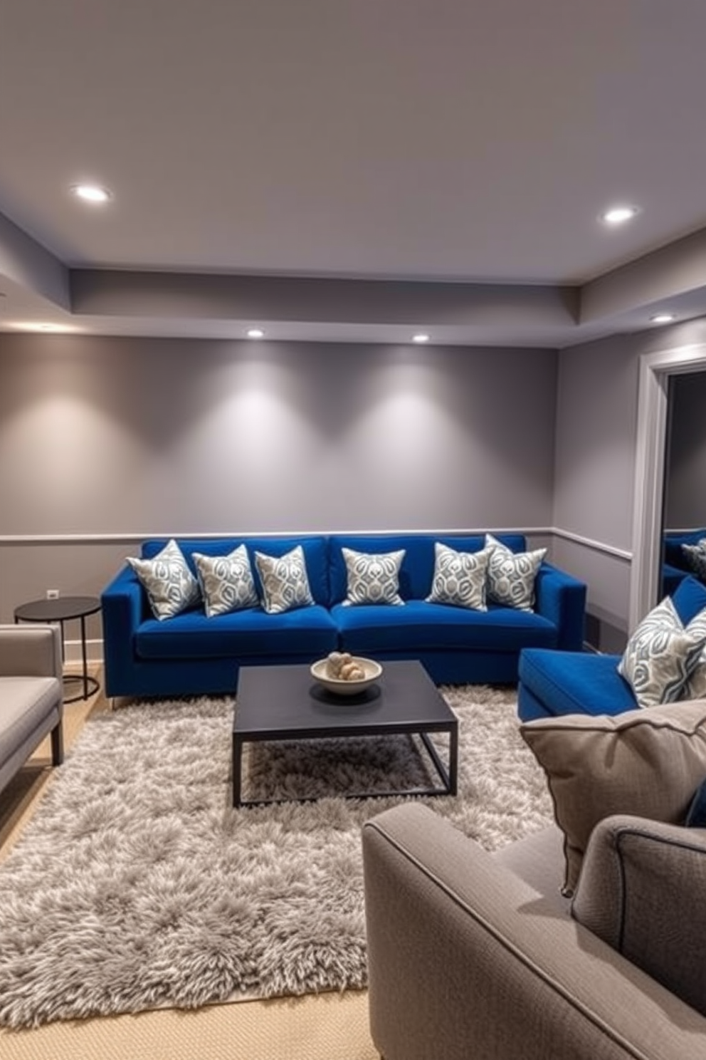 A stylish basement lounge featuring a blue sofa adorned with geometric patterned cushions. The space is illuminated by warm recessed lighting, creating a cozy atmosphere for relaxation and entertainment. The walls are painted in a soft gray tone, complementing the blue sofa beautifully. A plush area rug anchors the seating area, while a modern coffee table sits in the center, enhancing the contemporary design.