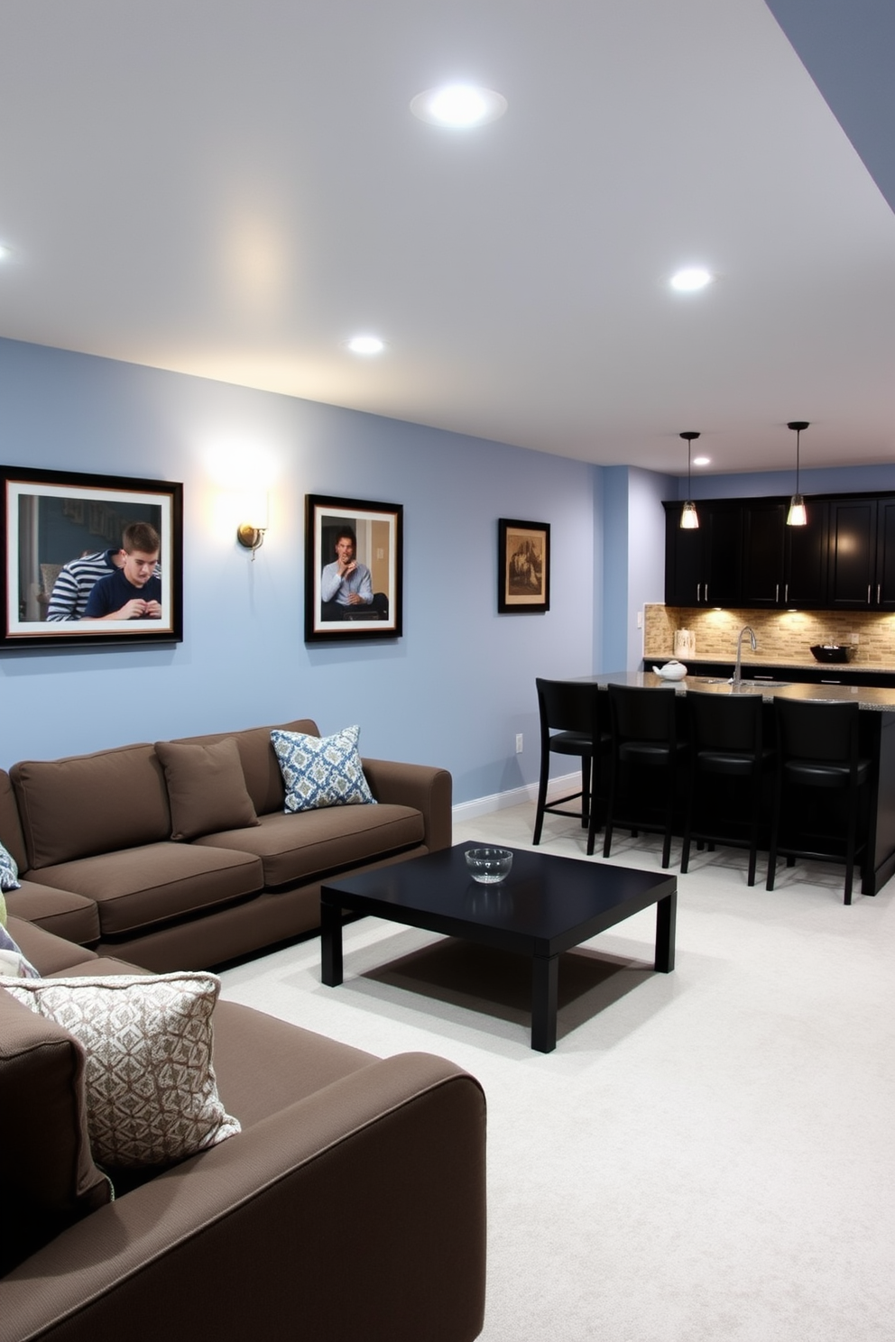 A cozy basement retreat featuring light blue walls that create a calming atmosphere. The space is furnished with dark wood furniture, including a plush sectional sofa and a sleek coffee table, contrasting beautifully with the wall color. In one corner, a home bar with dark cabinetry is accented by stylish bar stools. Soft lighting fixtures hang from the ceiling, adding warmth and enhancing the inviting ambiance of the room.