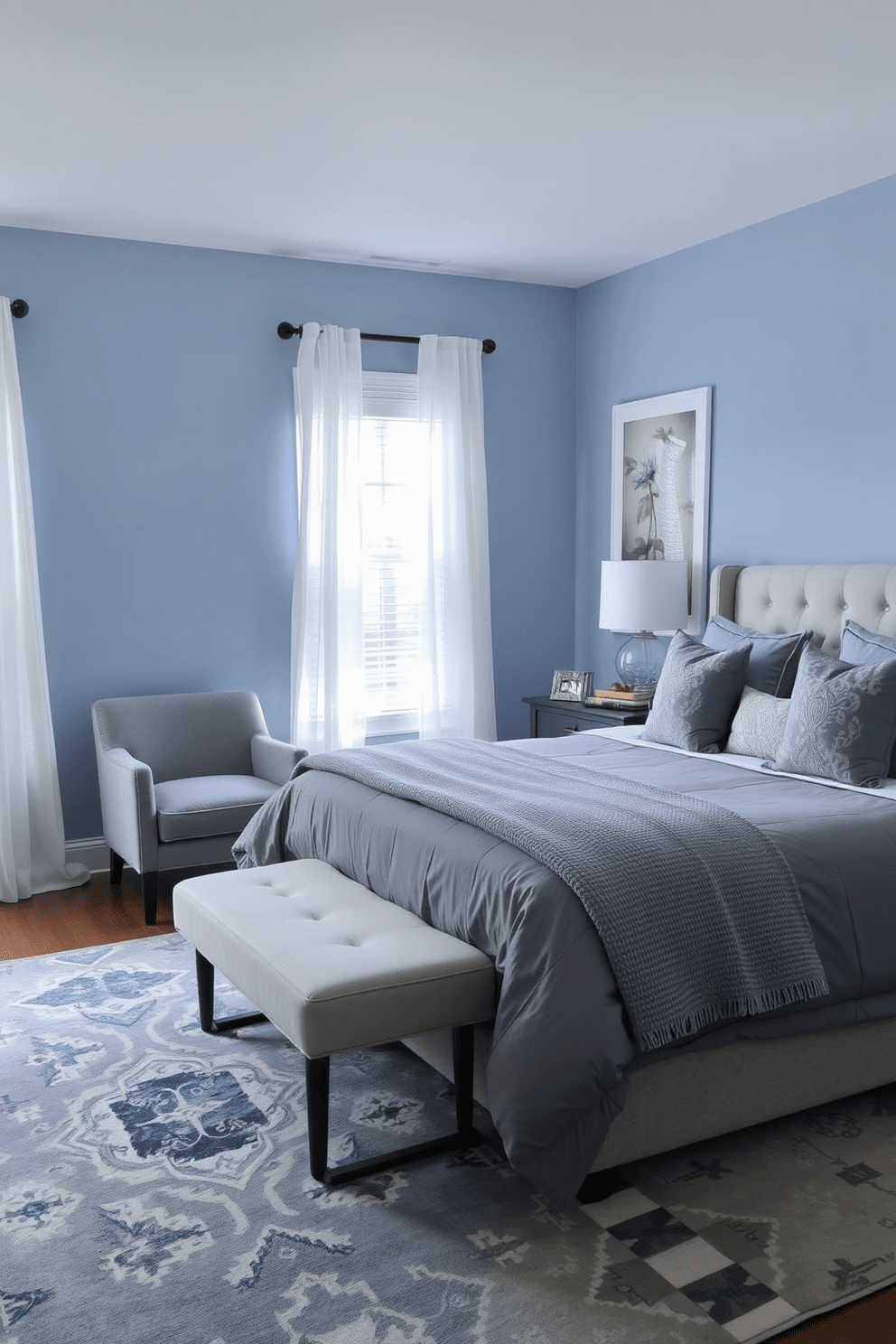 A serene blue and gray bedroom setting designed for tranquility. The walls are painted a soft blue, complemented by gray bedding and decorative pillows on a plush king-size bed. Natural light filters through sheer white curtains, illuminating a cozy reading nook with a gray armchair and a small side table. A stylish area rug in shades of blue and gray anchors the space, adding warmth and comfort.