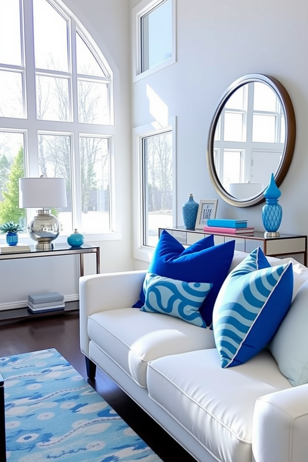 Bright blue accent pillows are arranged on a plush white sofa, adding a pop of color to the inviting living space. The room features large windows that allow natural light to flood in, enhancing the vibrant hues of the decor. The foyer is designed with a sleek console table against the wall, topped with a stylish lamp and decorative items. A large round mirror hangs above the table, reflecting the bright blue accents throughout the space and creating a cohesive look.