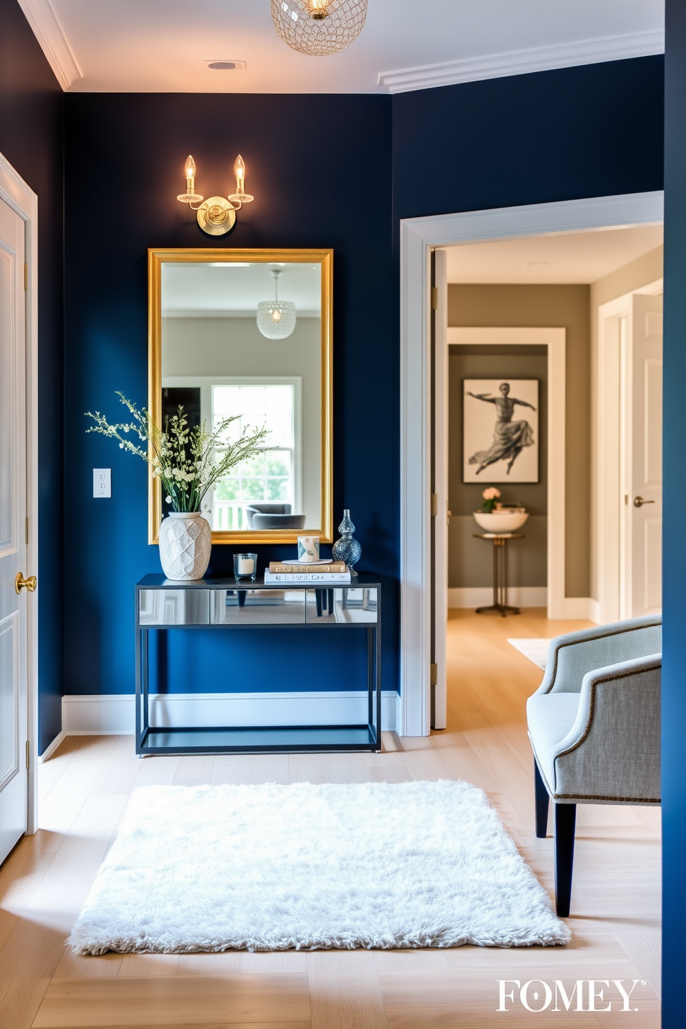 A striking foyer features a midnight blue accent wall adorned with elegant sconces that cast a warm glow. The space is complemented by a sleek console table topped with decorative items and a large mirror that enhances the room's depth. The floor is finished in a light wood, providing a beautiful contrast to the dark wall. A plush area rug in soft neutrals anchors the space, inviting guests into a stylish and welcoming entryway.