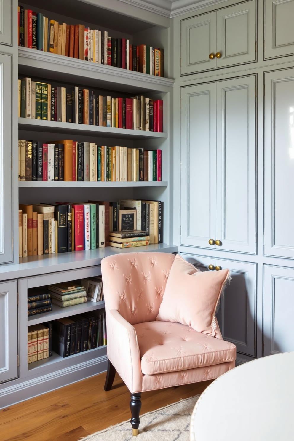 A cozy home library features light blue cabinetry with brass hardware that adds a touch of elegance. The shelves are filled with a curated collection of books, and a plush reading chair sits invitingly in the corner.