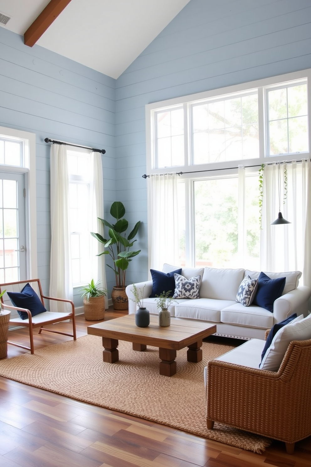 A cozy living room featuring light blue shiplap walls that create a rustic yet inviting atmosphere. The space is adorned with a plush white sofa, complemented by navy blue throw pillows and a reclaimed wood coffee table at the center. Natural light floods in through large windows dressed with sheer white curtains, enhancing the tranquil ambiance. A woven area rug in soft beige anchors the seating area, while potted plants add a touch of greenery to the decor.