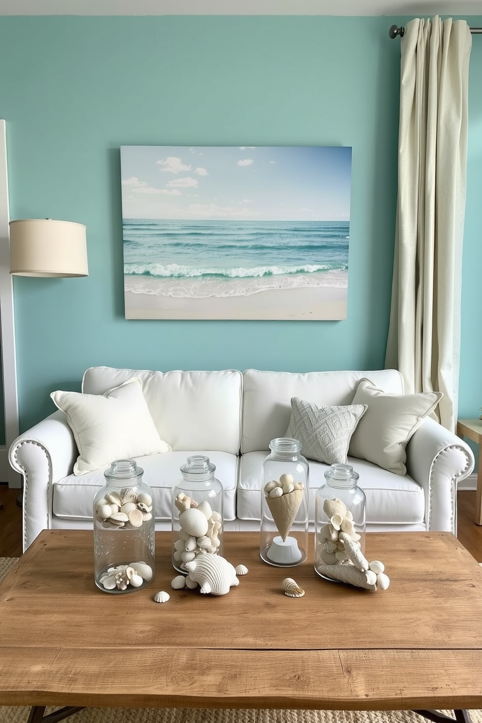 Ocean inspired decor with seashells. The walls are painted in a soft aquamarine hue, and a large canvas featuring a serene beach scene hangs above a plush white sofa. Decorative accents include various seashells arranged in glass jars on a rustic wooden coffee table. The room is completed with light beige curtains that gently flutter in the ocean breeze.