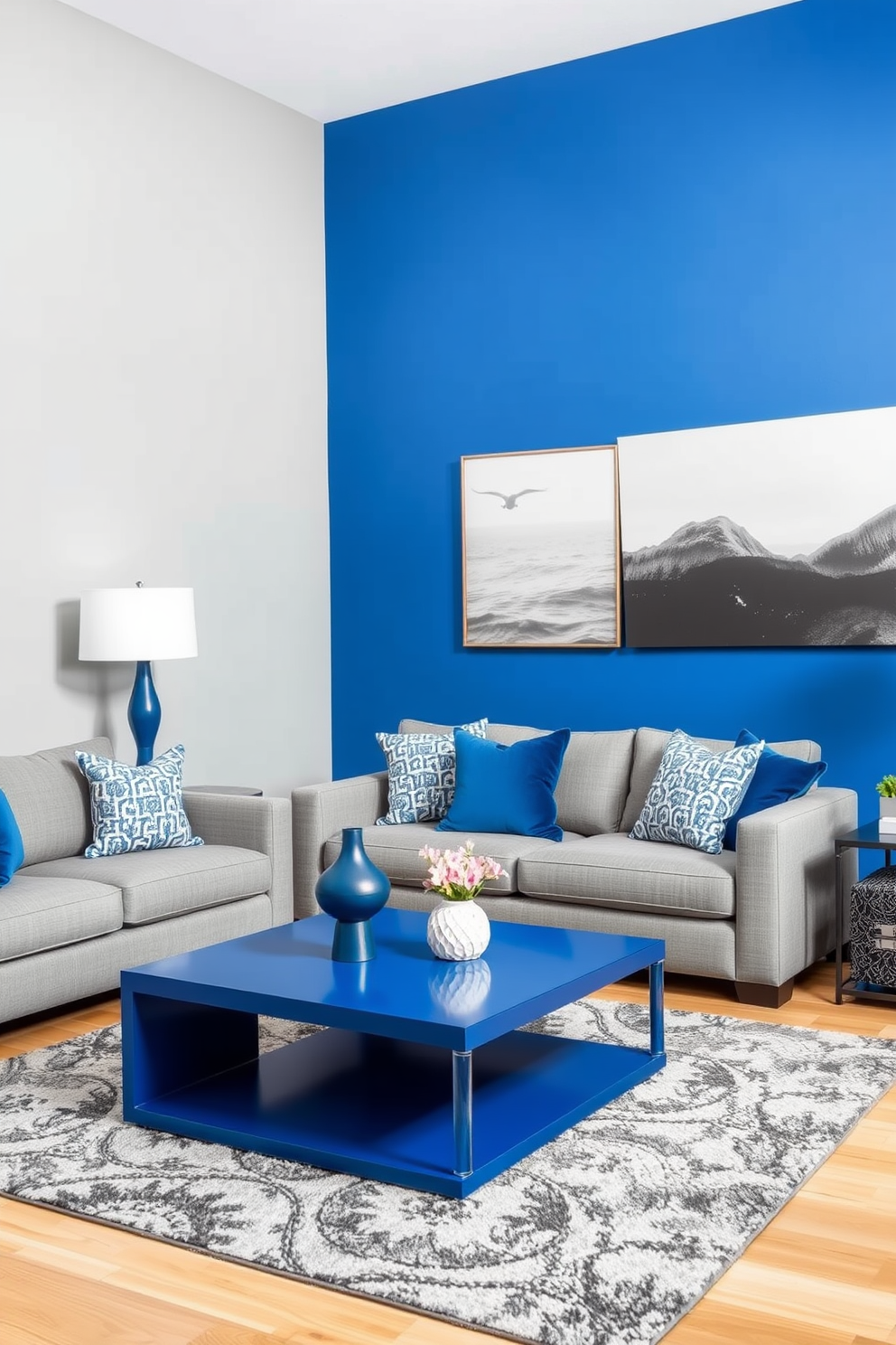 A stylish living room featuring a blue and gray color block design. The walls are painted in a soft gray, while one accent wall showcases a vibrant blue hue, creating a striking contrast. The furniture includes a plush gray sofa adorned with blue accent pillows. A sleek blue coffee table sits in the center, complemented by a gray area rug that ties the space together.