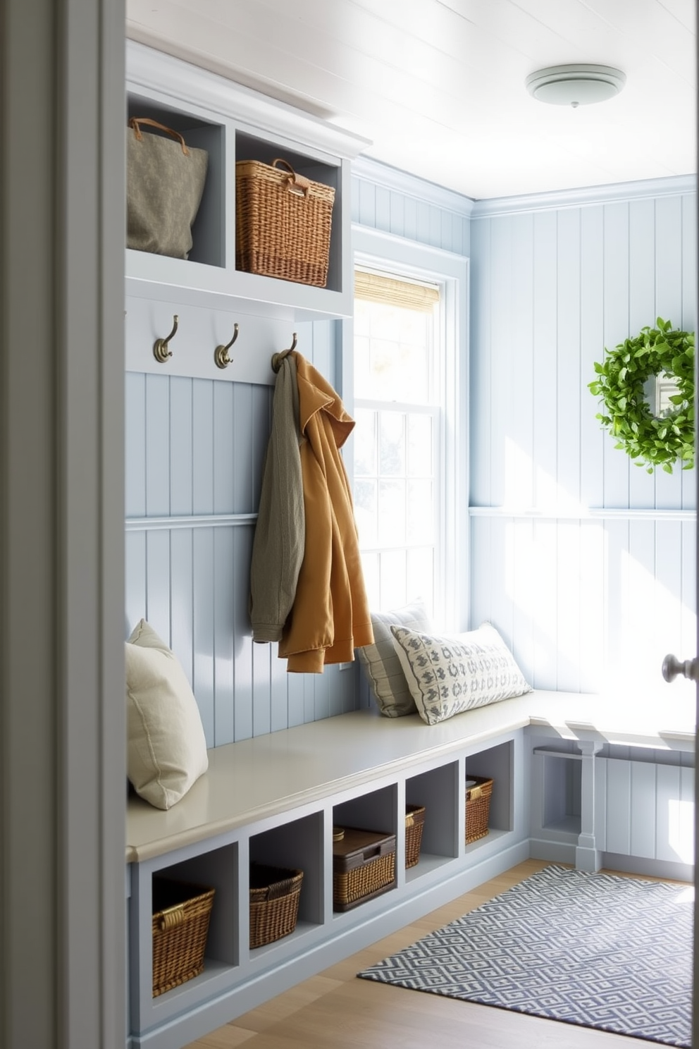 Light blue beadboard paneling creates a charming and inviting atmosphere in the mudroom. The space features built-in storage benches with soft cushions and hooks for hanging coats, all complemented by natural light streaming through a nearby window.