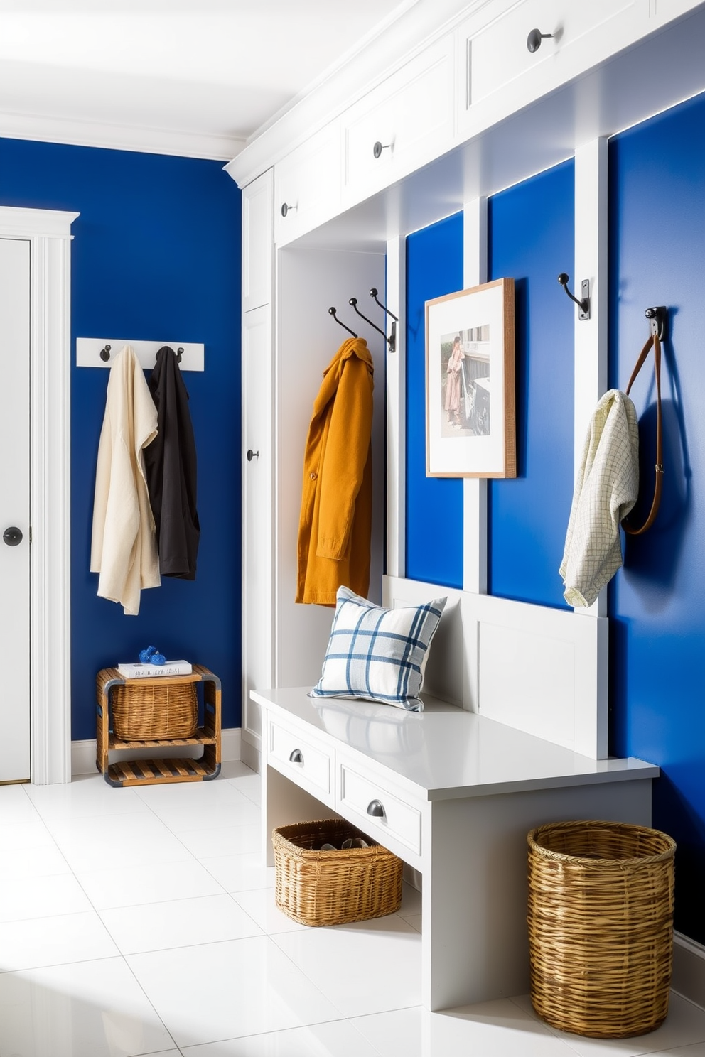 A rich cobalt blue mudroom features a striking accent wall that draws the eye immediately. The space is complemented by neutral elements such as a light gray bench and white cabinetry that provide a fresh contrast. The floor is adorned with large white tiles, enhancing the brightness of the room. Hooks for coats and a woven basket for shoes add functionality while maintaining an elegant aesthetic.