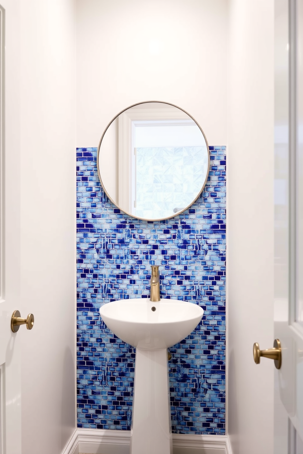 A stunning powder room features a unique backsplash made of blue mosaic tiles that catch the light beautifully. The walls are painted in a soft white shade, creating a fresh and airy atmosphere. A sleek pedestal sink sits against the wall, complemented by a modern faucet in brushed nickel. A round mirror with a thin frame hangs above the sink, reflecting the vibrant tiles and enhancing the room's elegance.