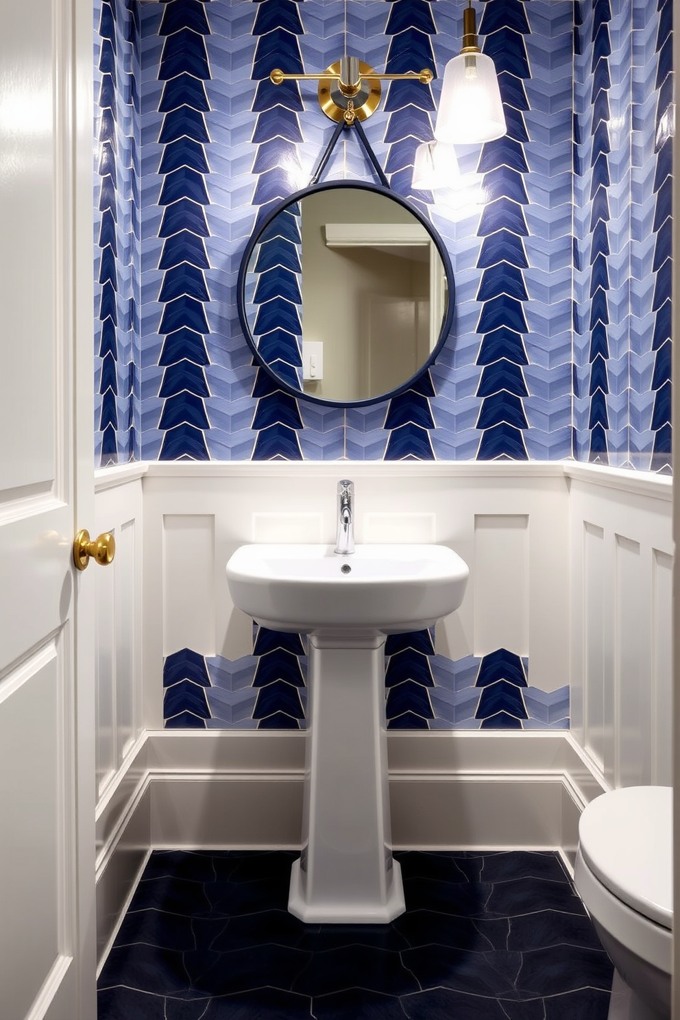 A stylish powder room featuring geometric patterned tiles in varying shades of navy. The walls are adorned with a sleek white wainscoting that complements the bold tile design. A modern pedestal sink with a polished chrome faucet sits against the wall, accented by a round mirror with a thin navy frame. Soft lighting fixtures with a contemporary design illuminate the space, enhancing the rich blue tones.