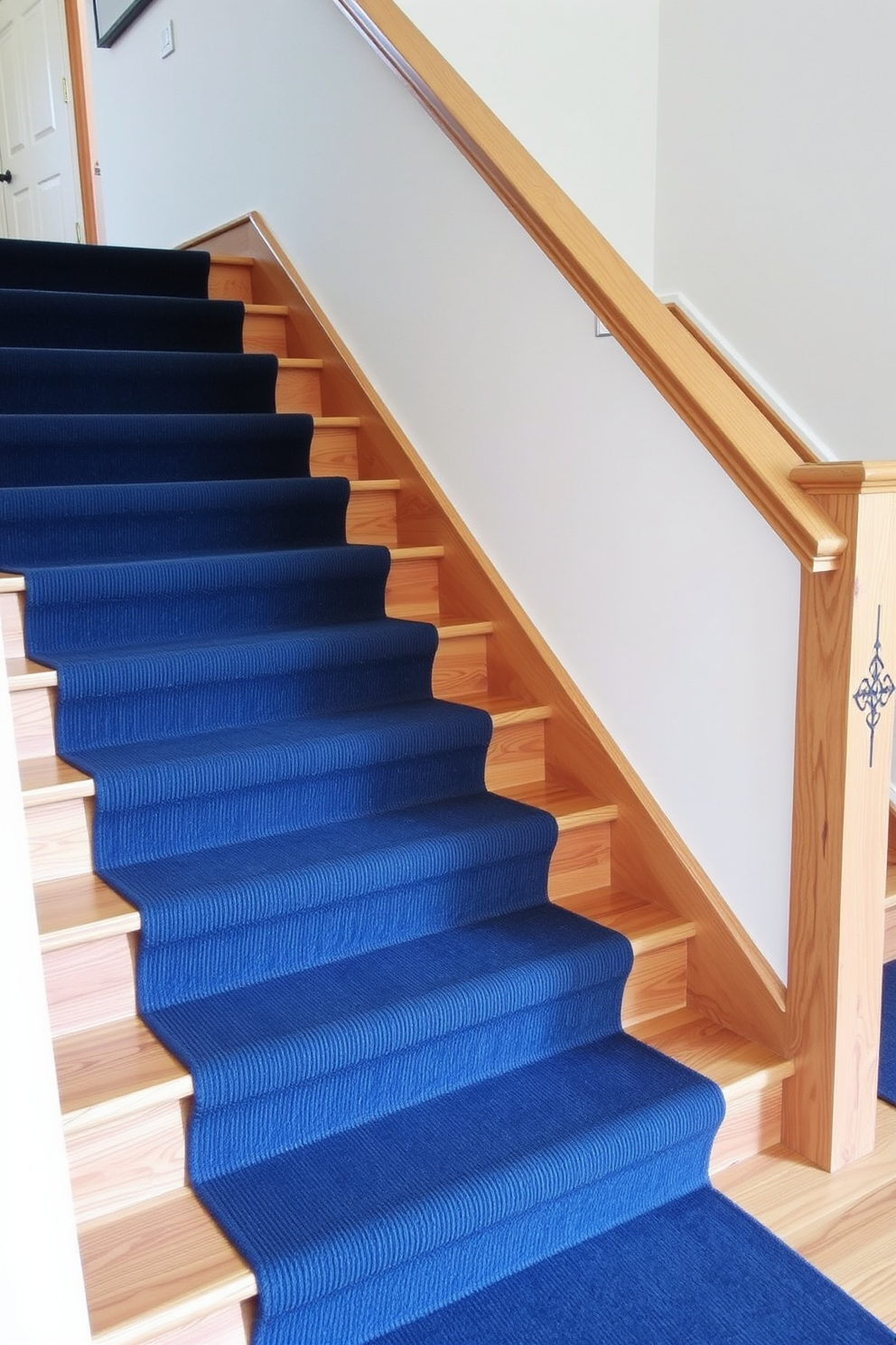 A navy blue carpet runner elegantly lines the wooden staircase, providing a striking contrast against the natural wood tones. The runner features a subtle geometric pattern that adds texture and visual interest to the space. The staircase itself is designed with clean lines and a sleek banister, enhancing the modern aesthetic of the home. Soft lighting illuminates the staircase, creating a warm and inviting atmosphere as it guides guests to the upper levels.