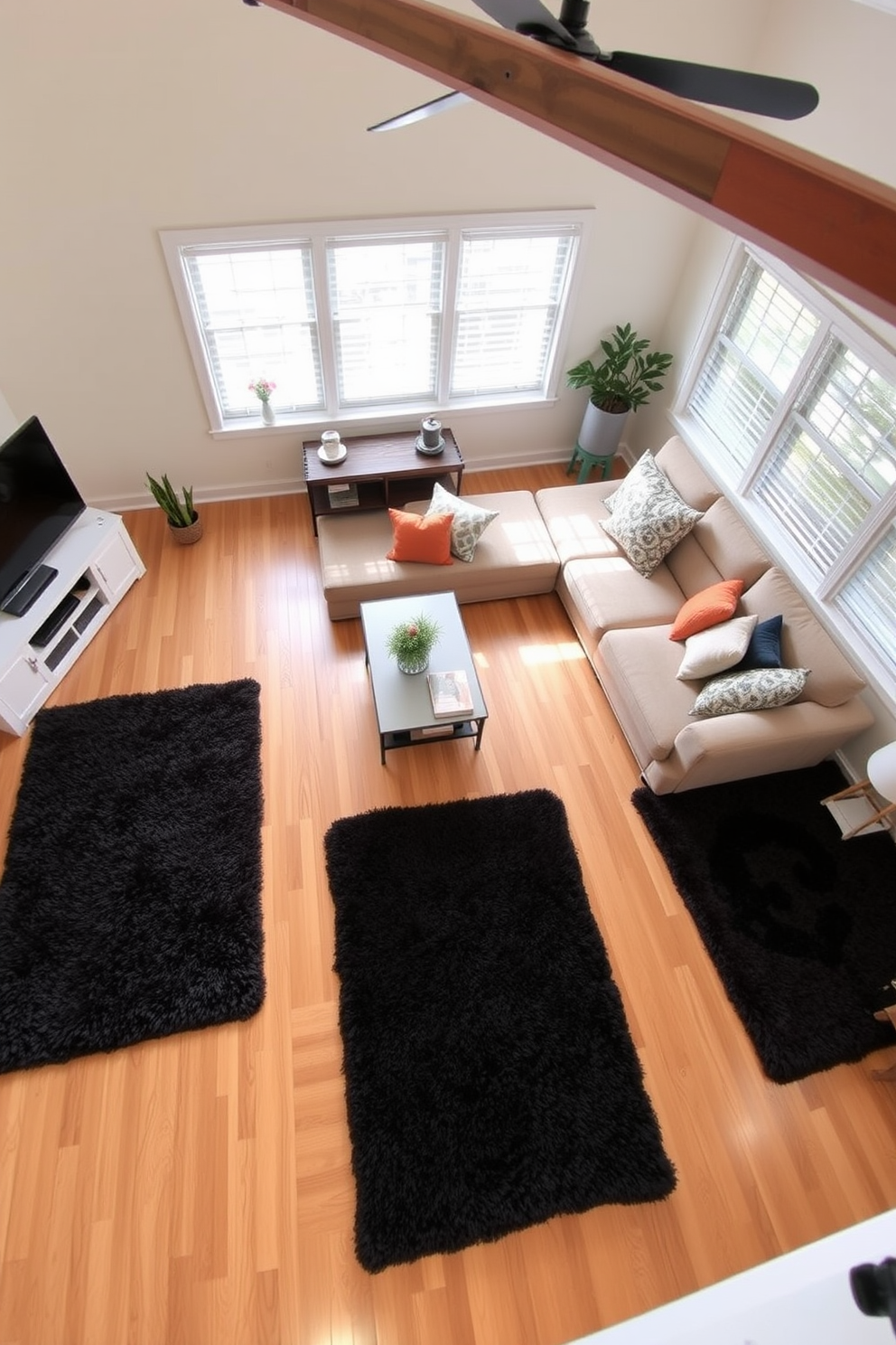 A cozy living room featuring light brown hardwood flooring complemented by plush dark area rugs. The space is adorned with a large sectional sofa in a neutral tone, accented by colorful throw pillows and a stylish coffee table in the center.