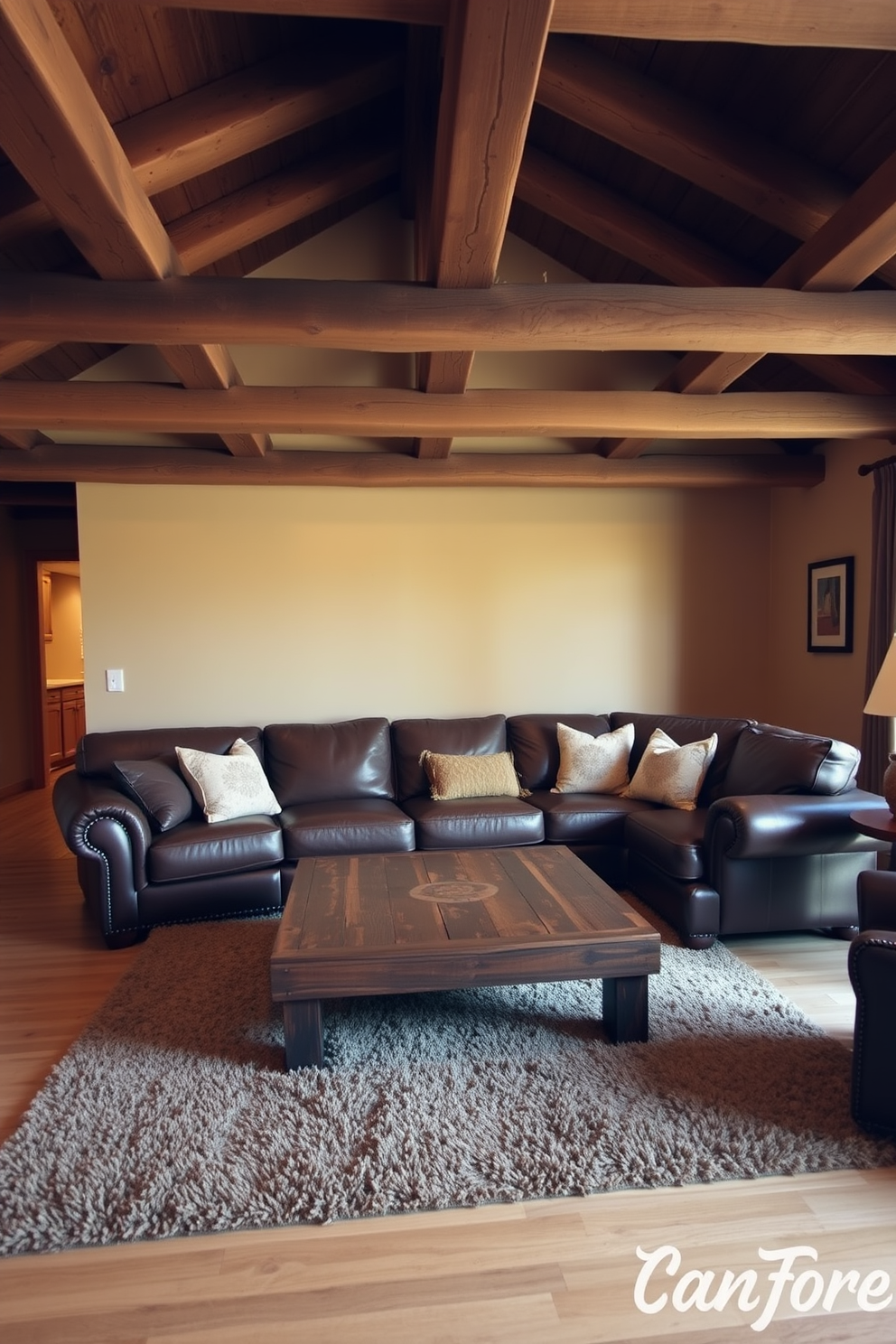 A cozy living room with natural wood beams exposed on the ceiling creates a rustic atmosphere. The walls are painted in a warm beige tone, and a large brown leather sectional sofa is positioned in the center of the room. A reclaimed wood coffee table sits in front of the sofa, surrounded by a plush area rug in earthy tones. Decorative throw pillows in various shades of brown and cream add comfort and style to the seating area.