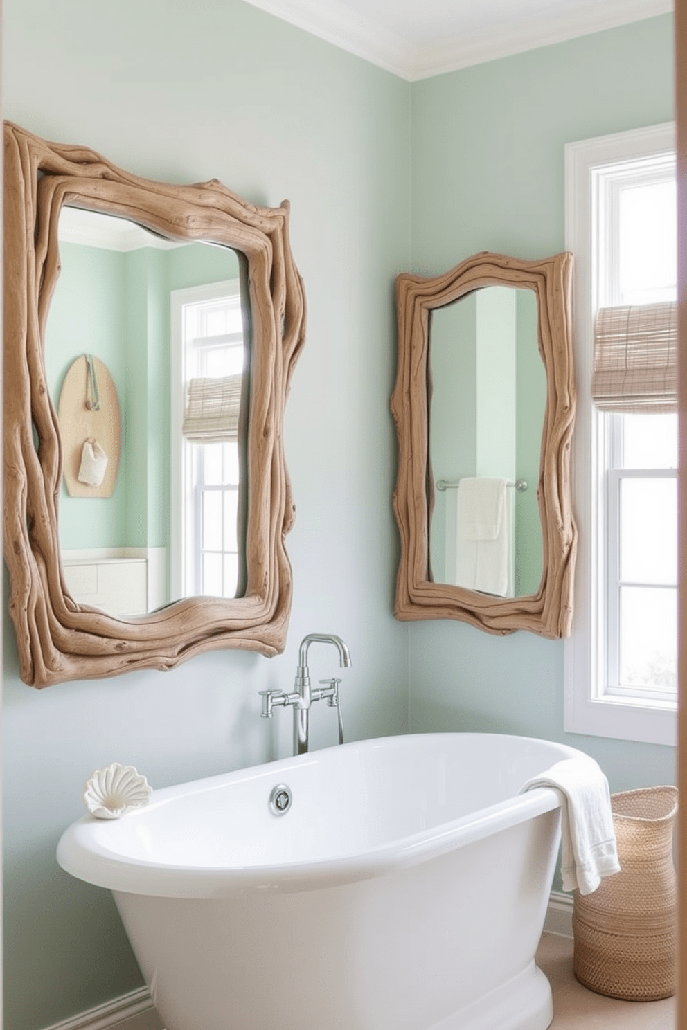 Driftwood mirrors frame a serene coastal bathroom setting. The walls are painted in soft seafoam green, complemented by sandy beige accents. A freestanding soaking tub sits beneath a large window, allowing natural light to fill the space. Nautical-themed decor, such as seashells and coral, adds a touch of charm.