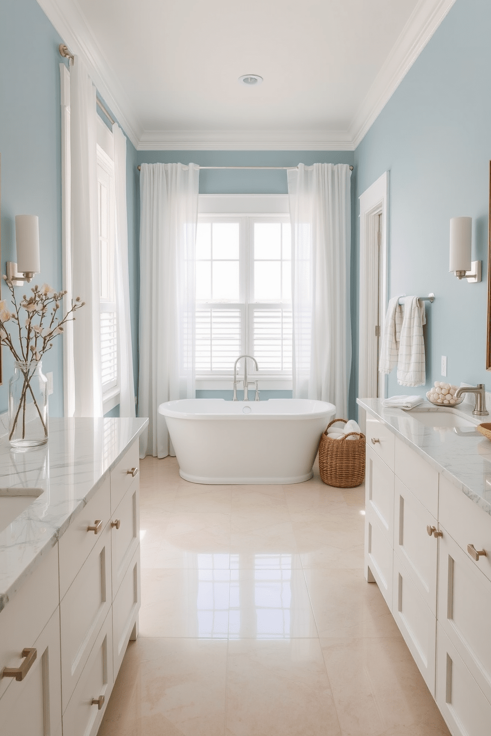 A coastal bathroom design featuring marble countertops that exude luxury and sophistication. The space includes soft blue walls, a freestanding soaking tub, and natural light streaming in through large windows with sheer white curtains. The flooring is a light, sandy beige tile that complements the coastal theme. Decorative elements include seashells in a glass jar and a woven basket filled with plush towels, creating a serene and inviting atmosphere.